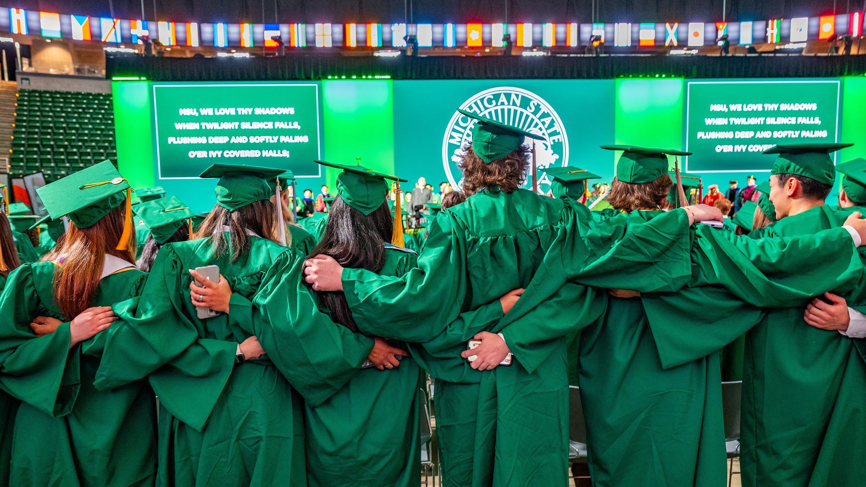 MSU graduates standing shoulder to shoulder viewed from behind