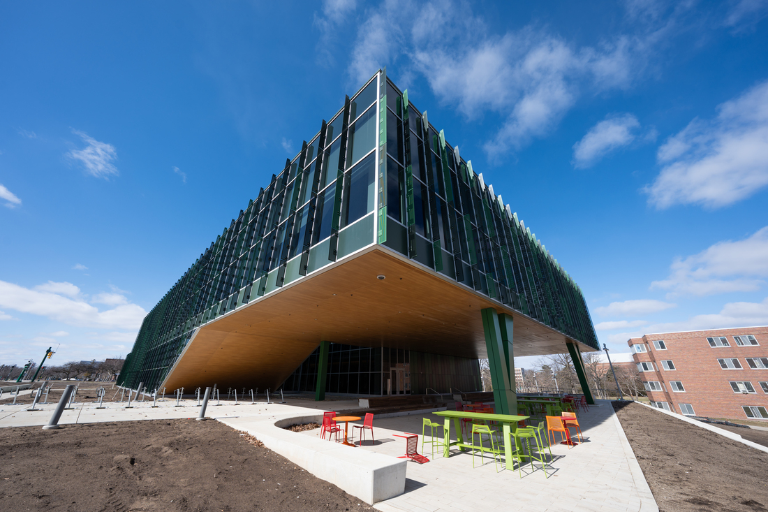 A large building that comes to a point with lots of windows and a blue sky background.