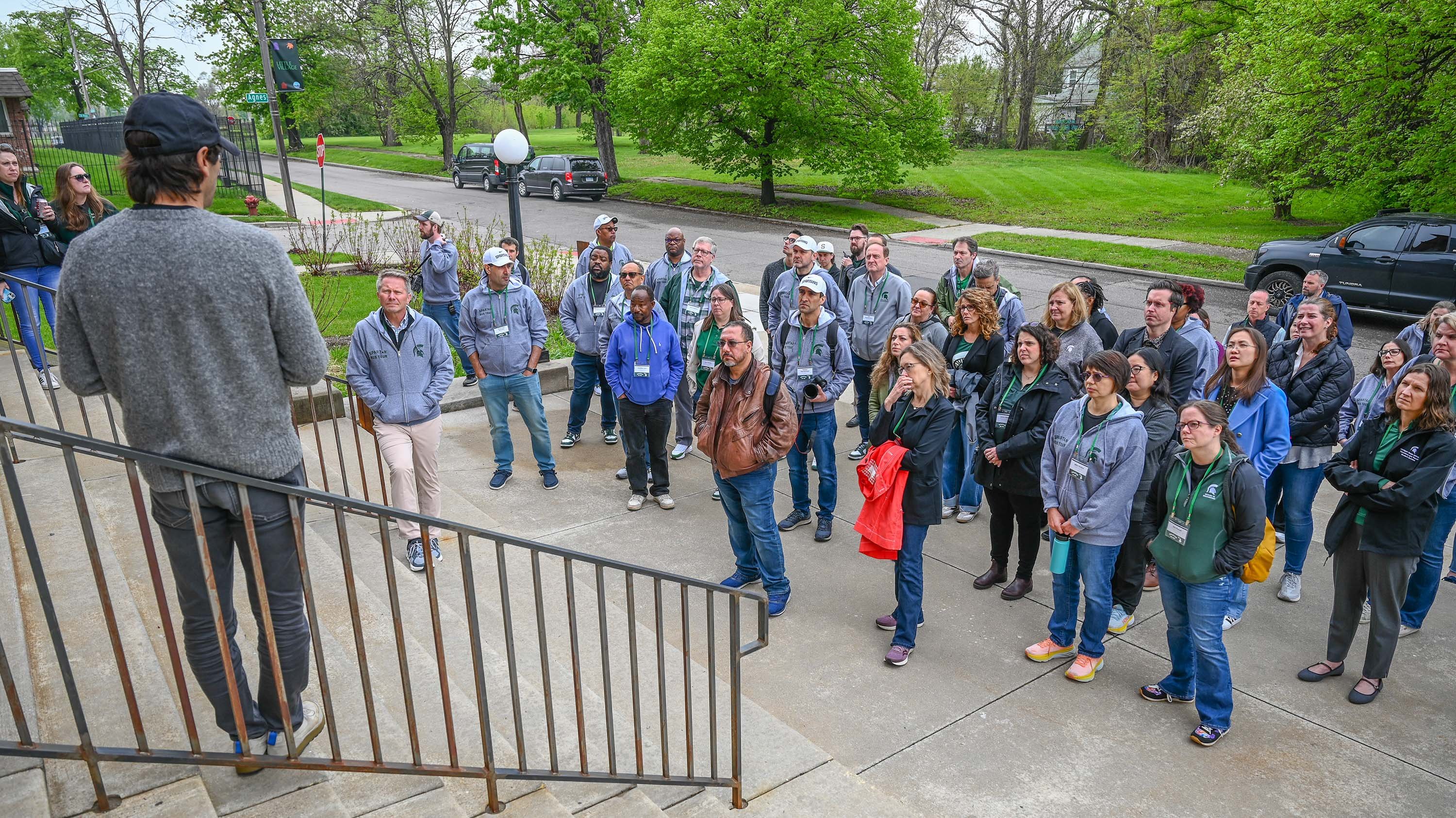 A man speaks to a group of people on the steps of a building
