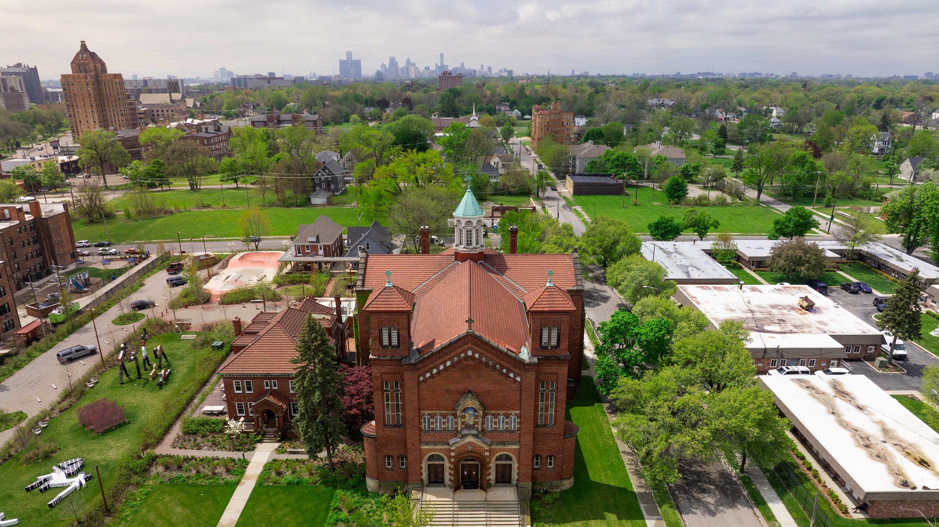An aerial view of an old church building with the Detroit skyline in the background