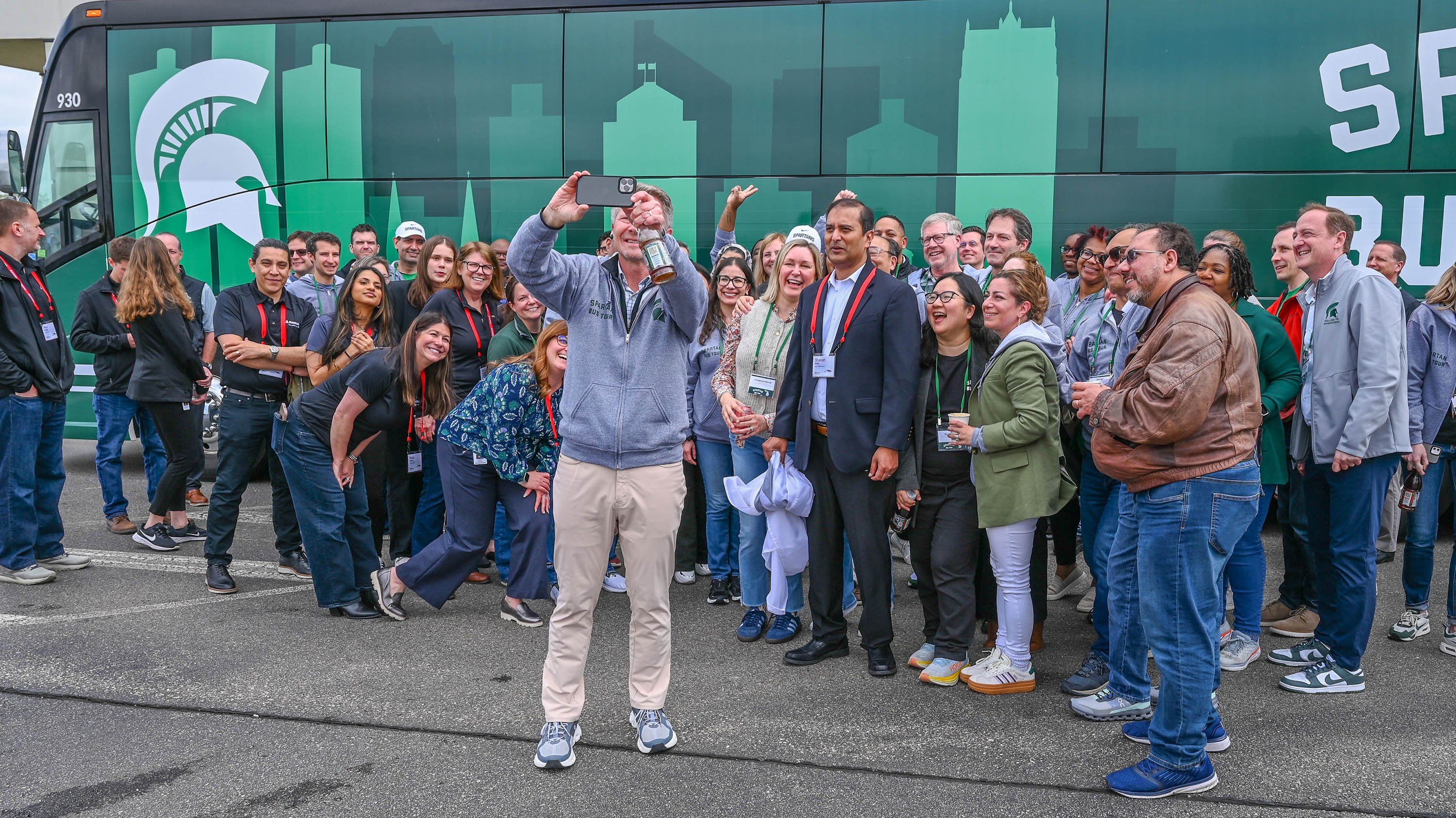 A man talking a selfie with a large group of people behind him.