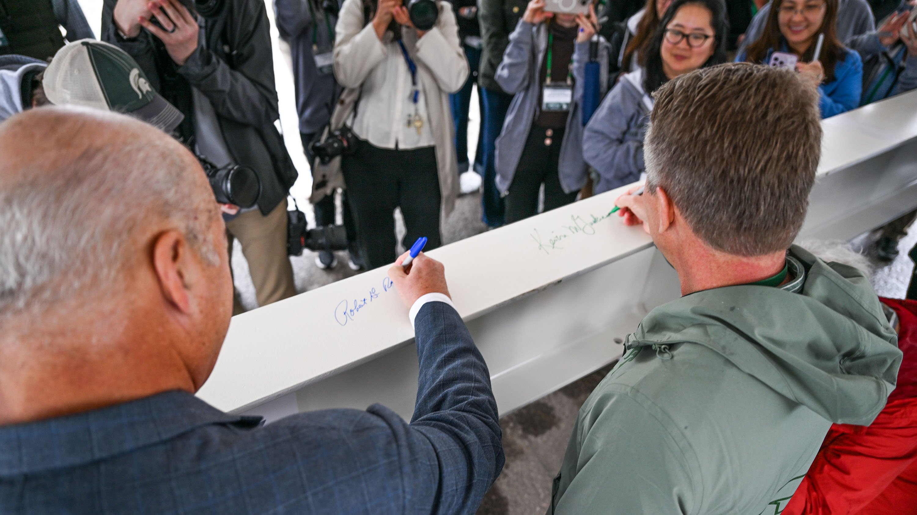 Two men signing a beam