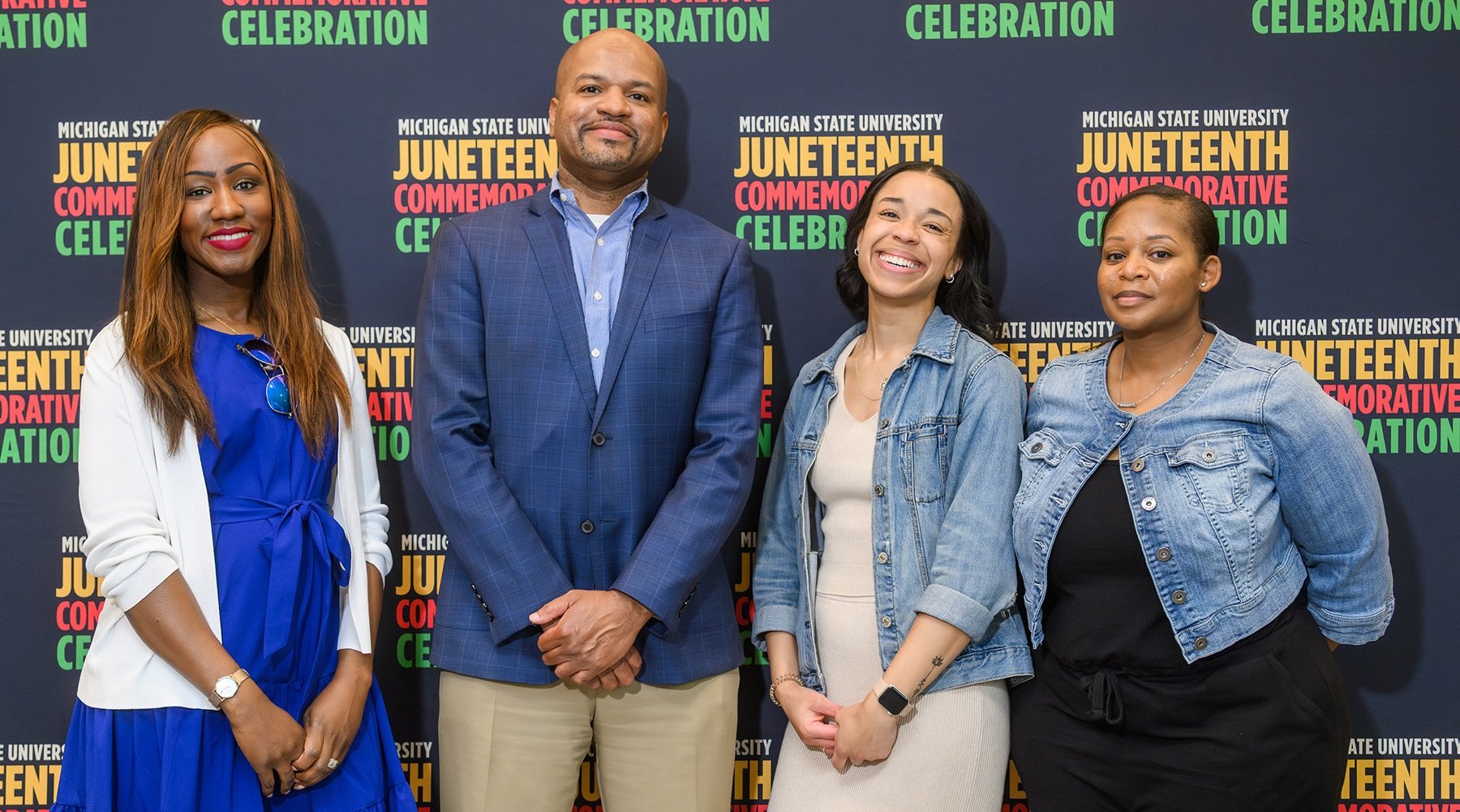 People pose in front of a Juneteenth backdrop