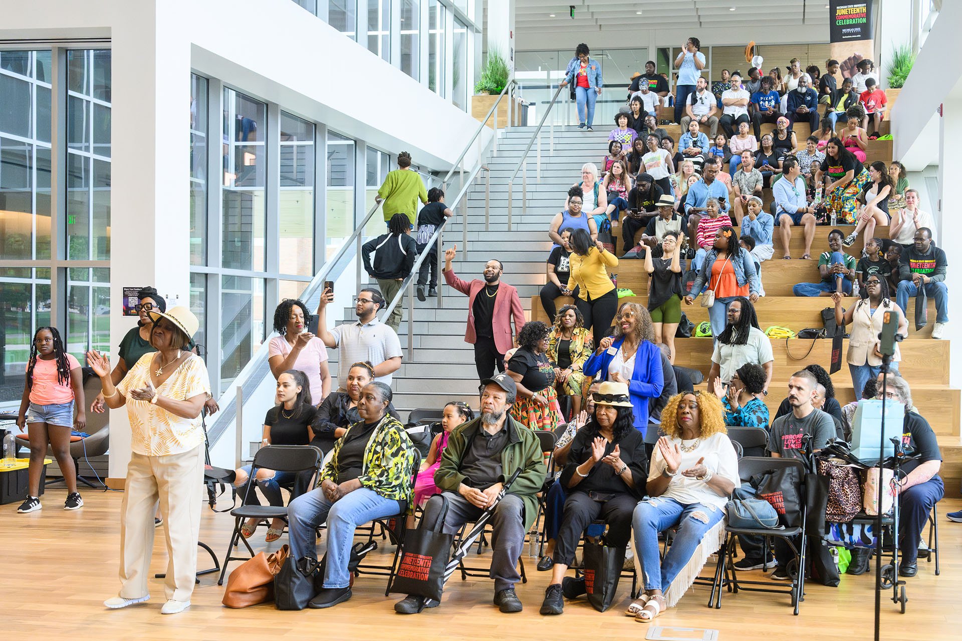 A large group sits on the Multicultural Center stairs at the MSU Juneteenth Celebration