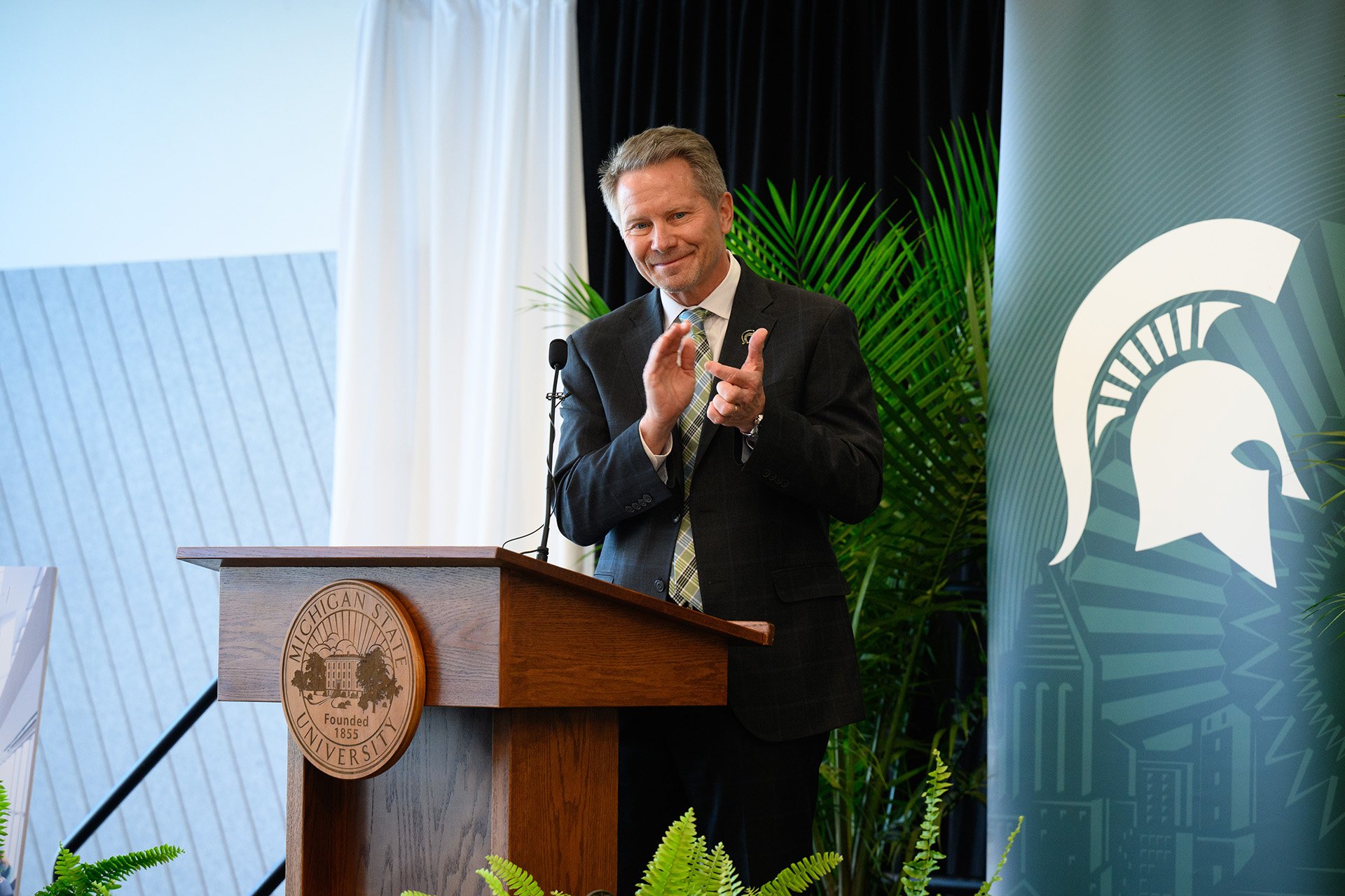 Kevin Guskiewicz applauding at the lectern