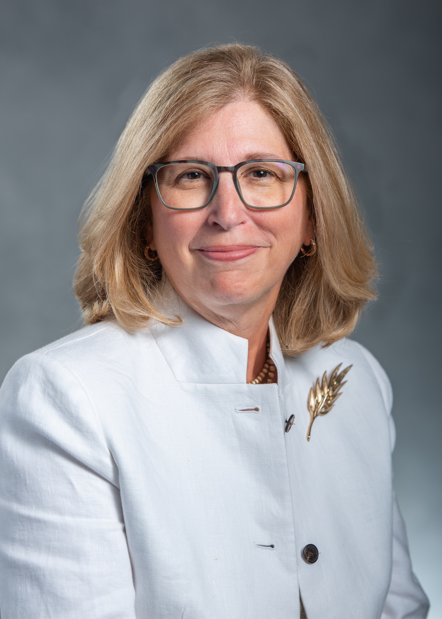 Portrait of Teresa Woodruff, smiling, wearing a white blazer