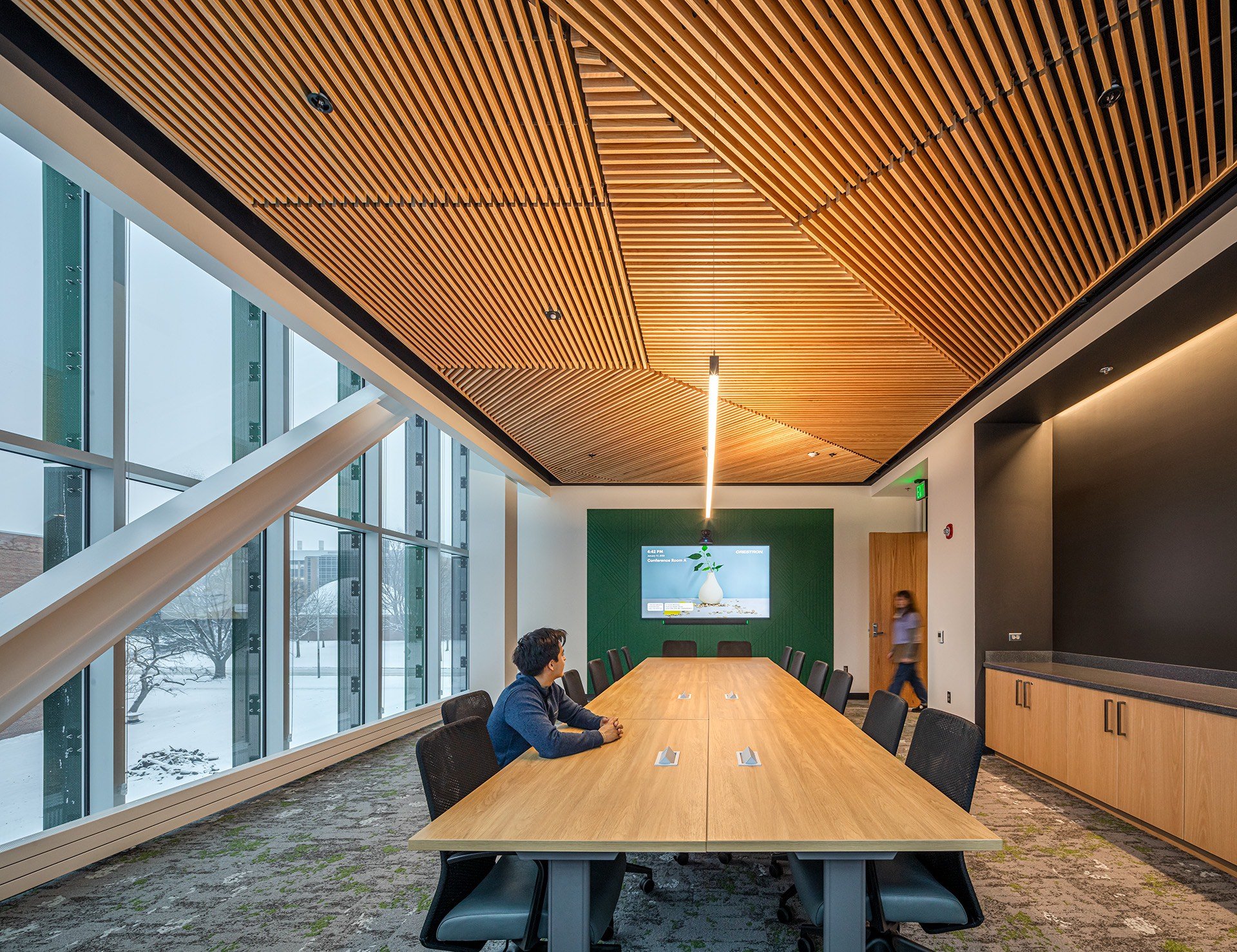 A person sits at a long table below a unique wood-paneled ceiling at the MSU Multicultural Center