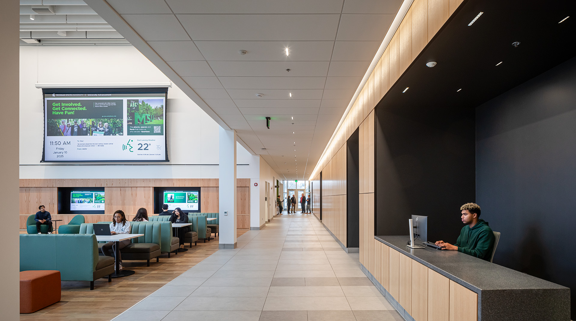 Interior of the MSU Multicultural Center at MSU with a view of a hallway and a seating area with a large screen showing campus information