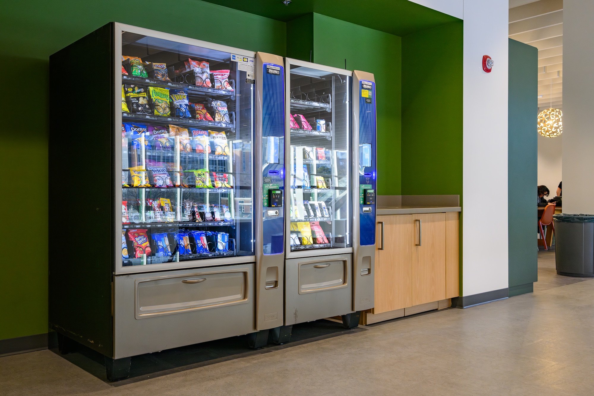 Two vending machines in a hallway in front of green walls at the MSU Multicultural Center
