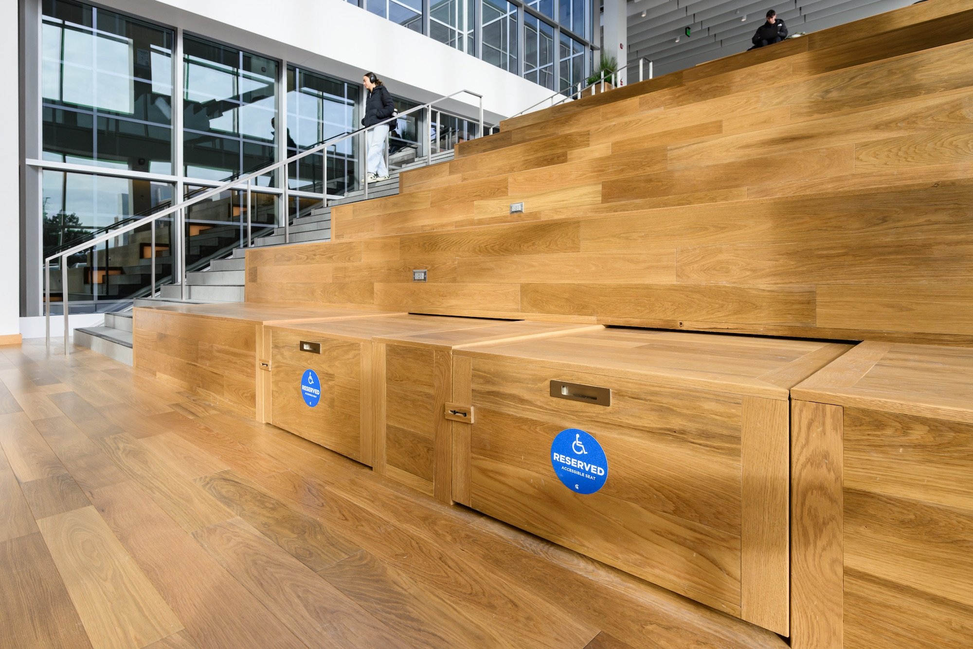 Wooden tiered seating area with blue handicap accessible signs posted on the bottom row of seats at the MSU Multicultural Center