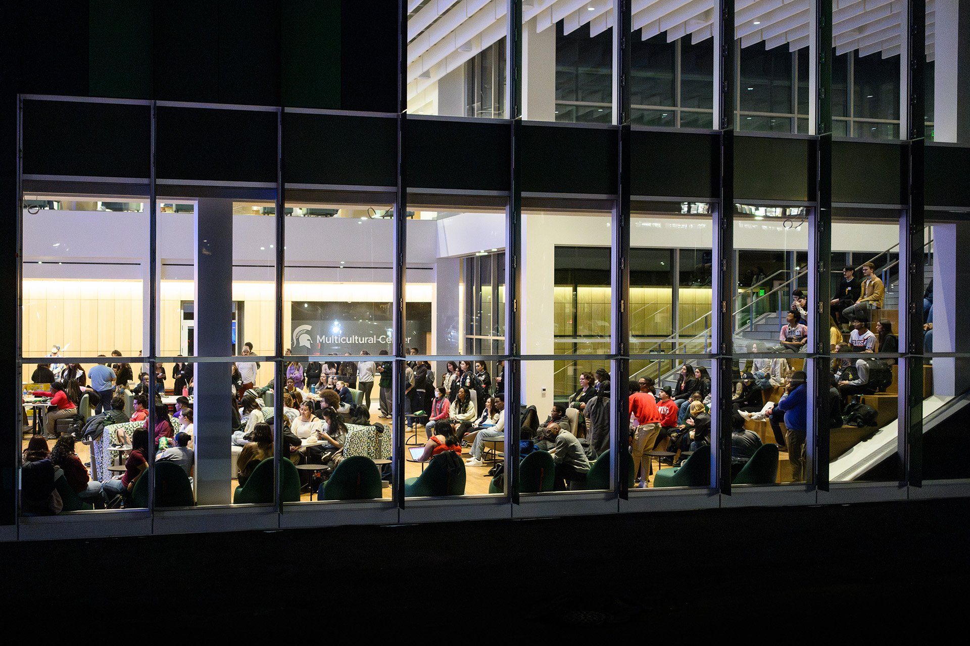 students illuminated from inside the Multicultural Center building