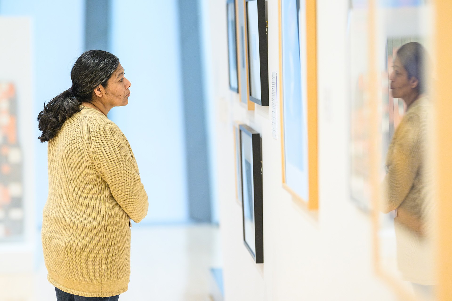 a woman takes a closer look at a framed art piece