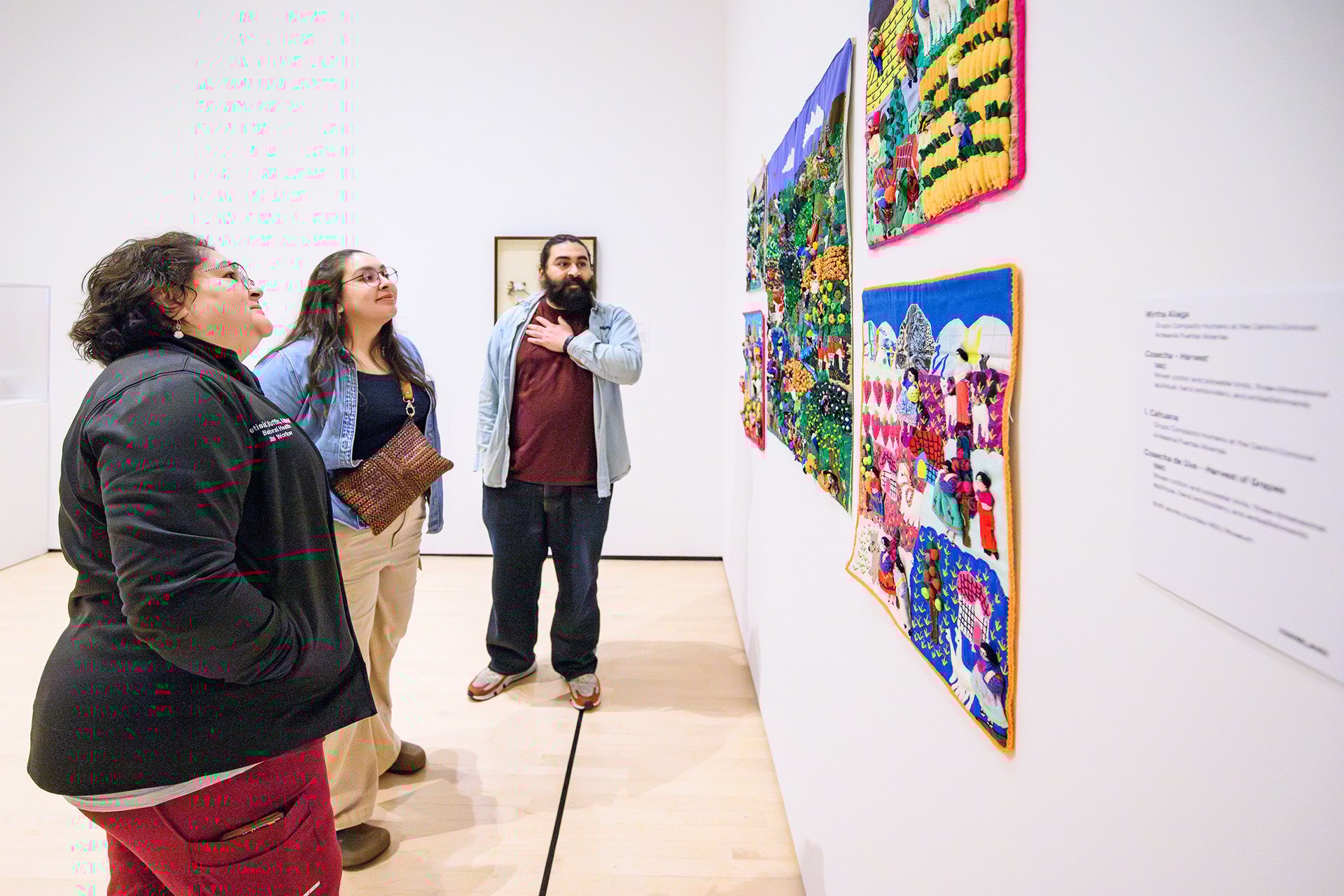guests peer at several quilts on the wall
