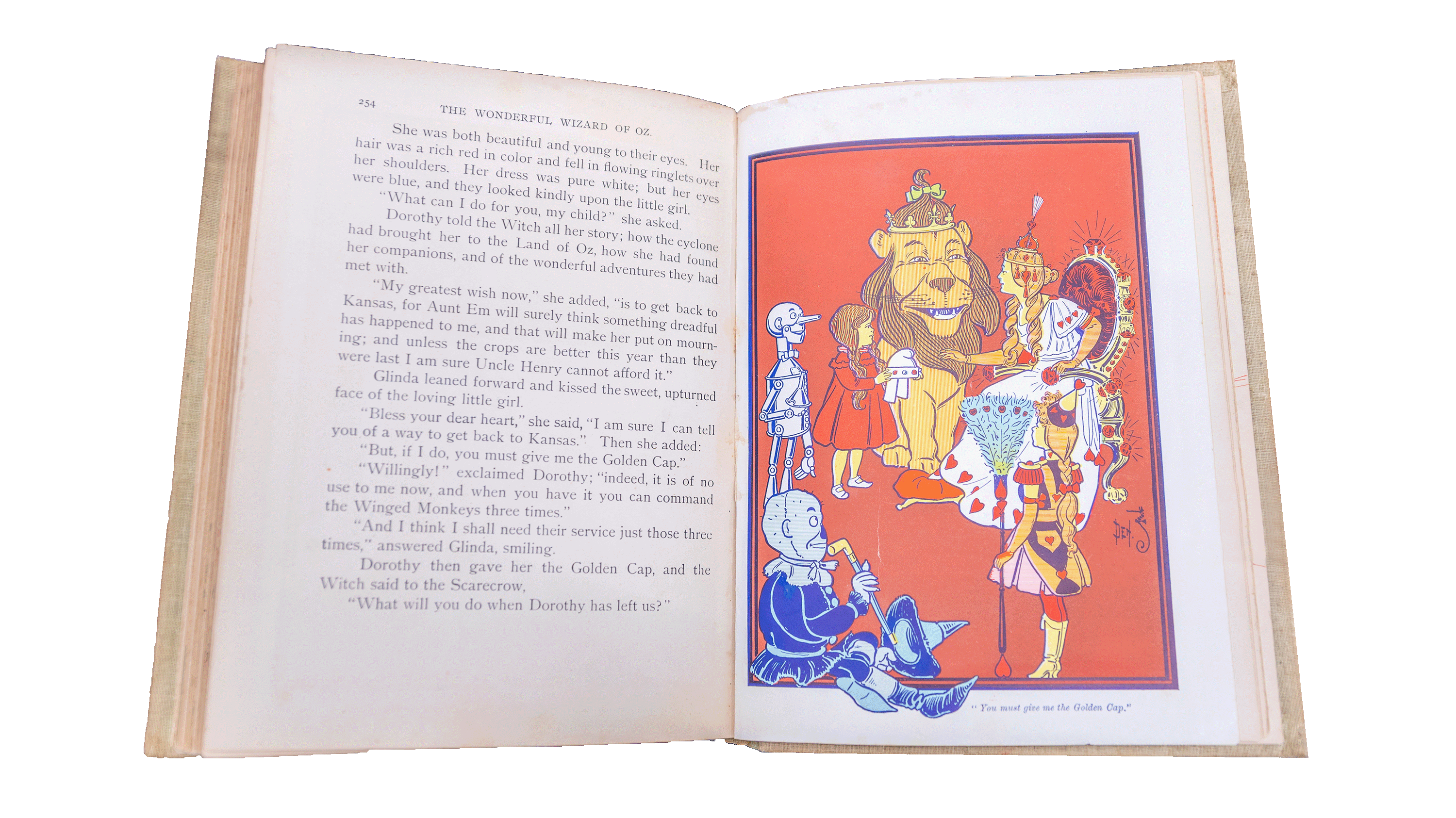 A look inside a vintage hardcover edition of The Wonderful Wizard of Oz by L. Frank Baum is displayed with text on the left page and an illustration of the cowardly lion, the tinman and dorothy on the right.