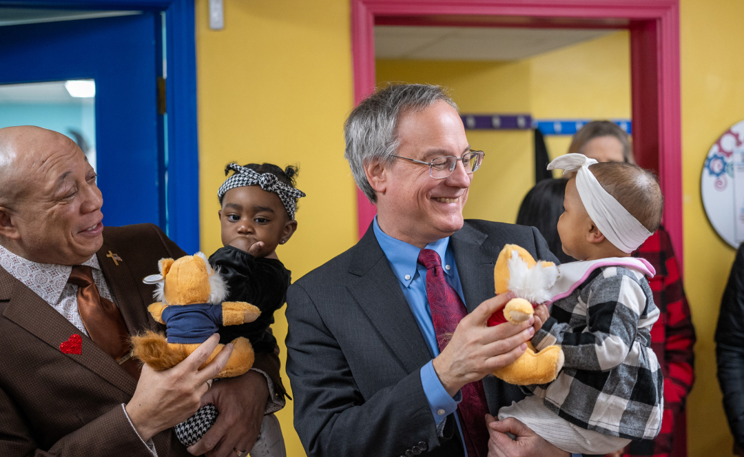 Aron Sousa, Executive Dean of MSU Health Colleges, holds child at Rx Kids' celebration. 