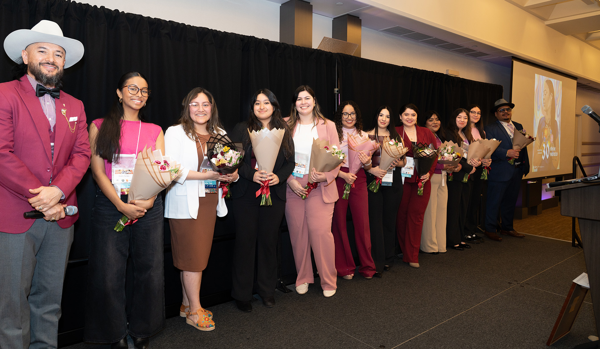 a row of participants wearing pink and holding bouquets 