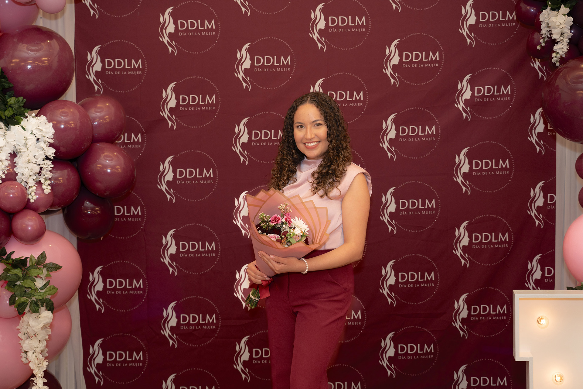 student holds a bouquet in front of backdrop
