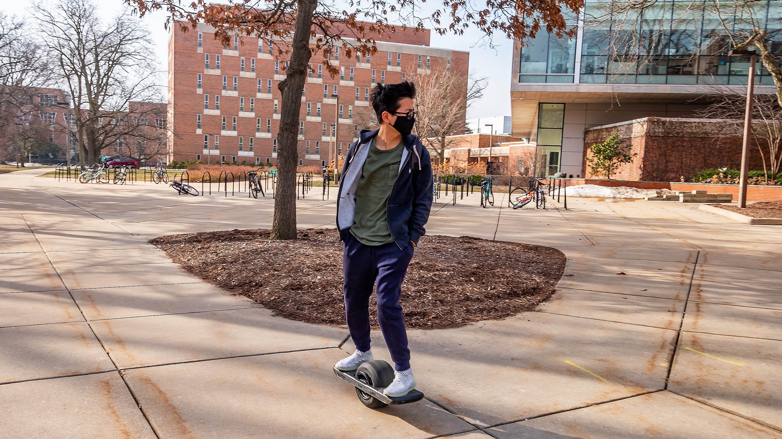 Student riding a one-wheel near Wells Hall