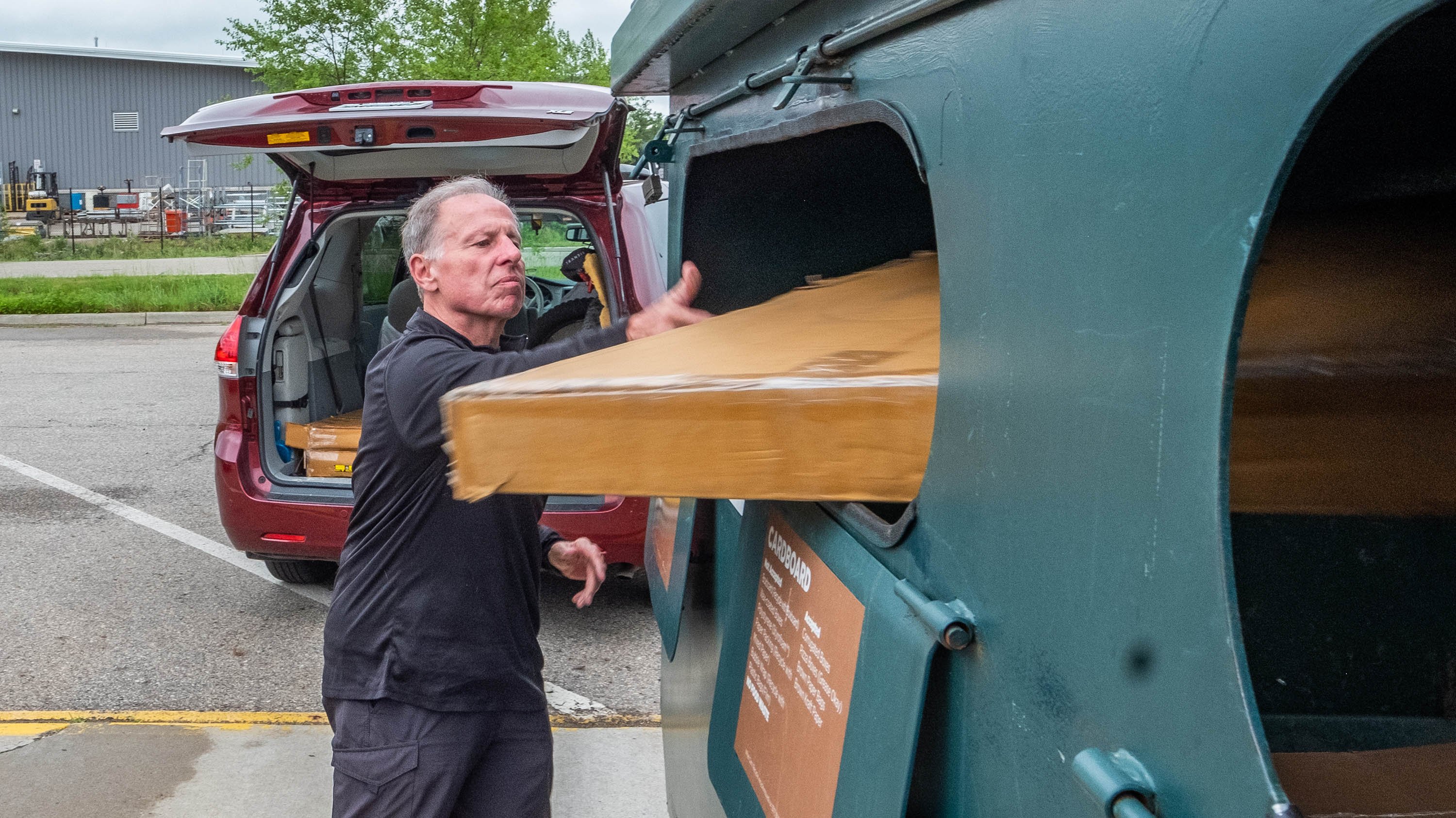 Man putting cardboard into a recycling container