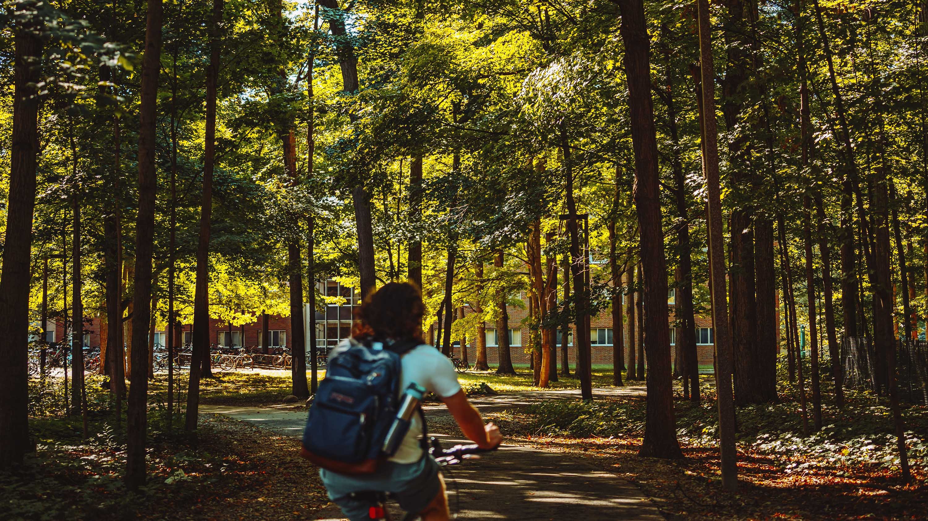 Student biking on campus near Wells Hall