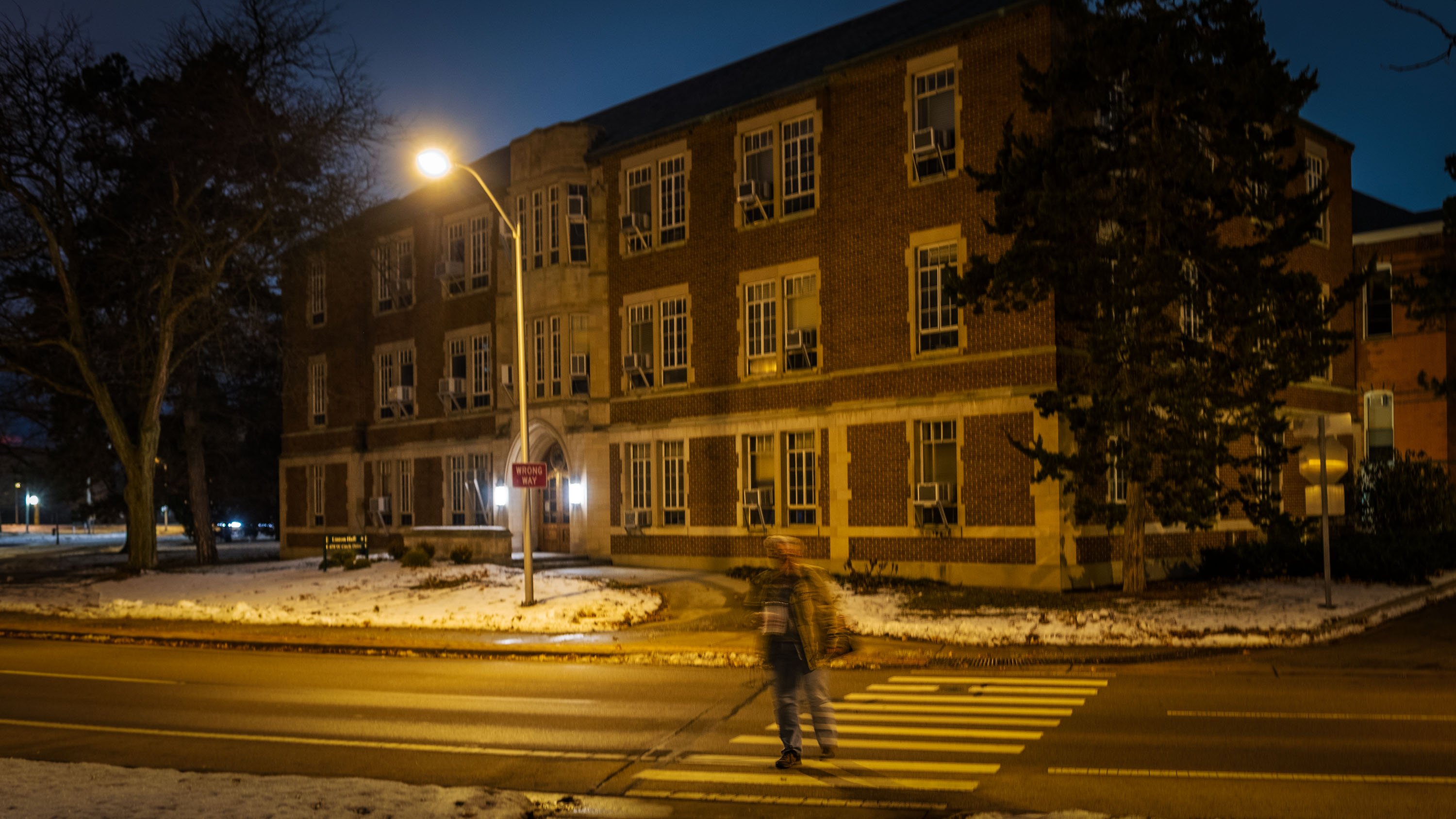 Image of a person walking at night with some motion blur, Linton Hall in the distance