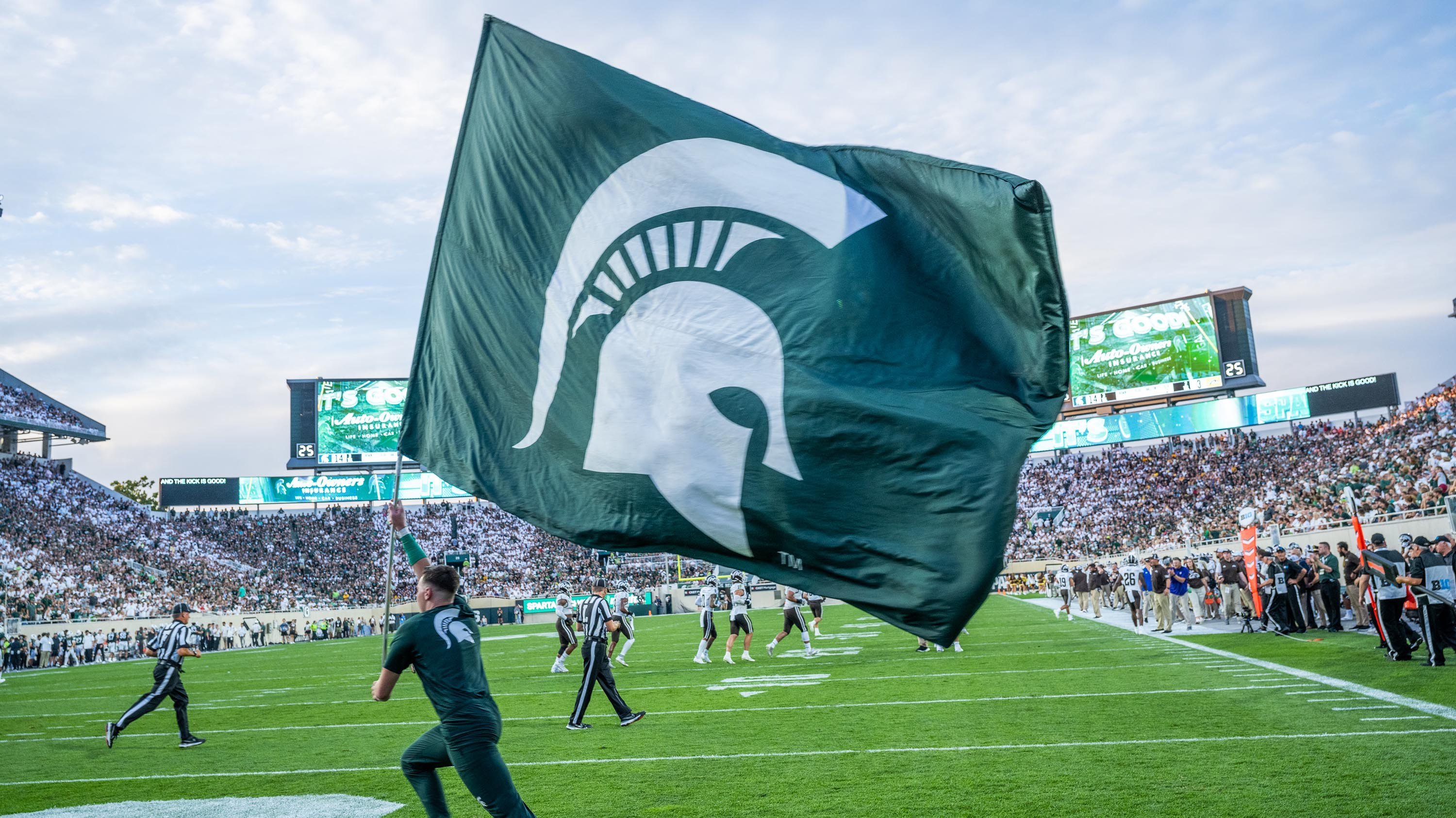 MSU cheerleader waving Spartan helmet flag