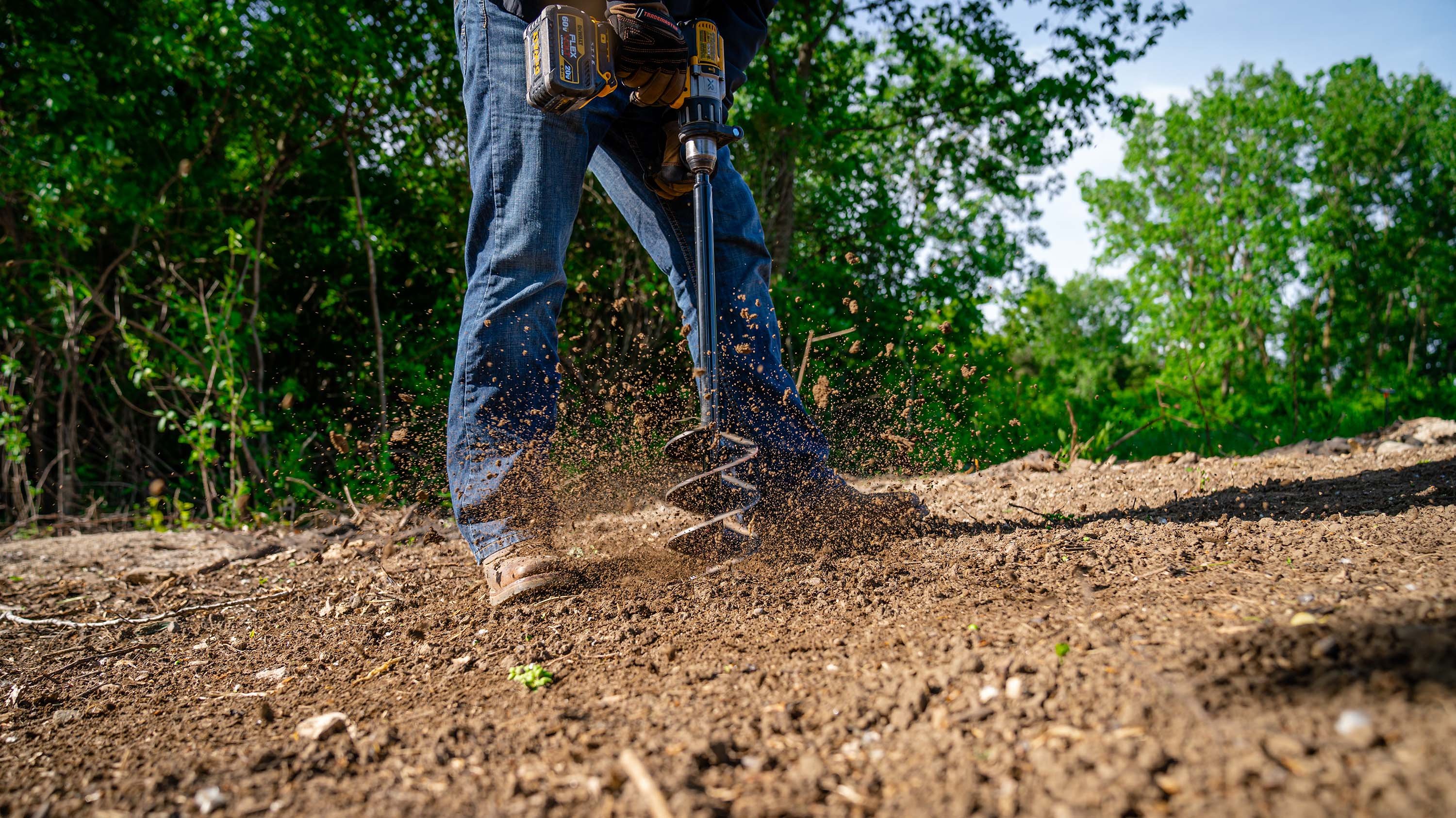 A photograph shows a drill with a post-hole digger attachment boring into a bare patch of soil. 