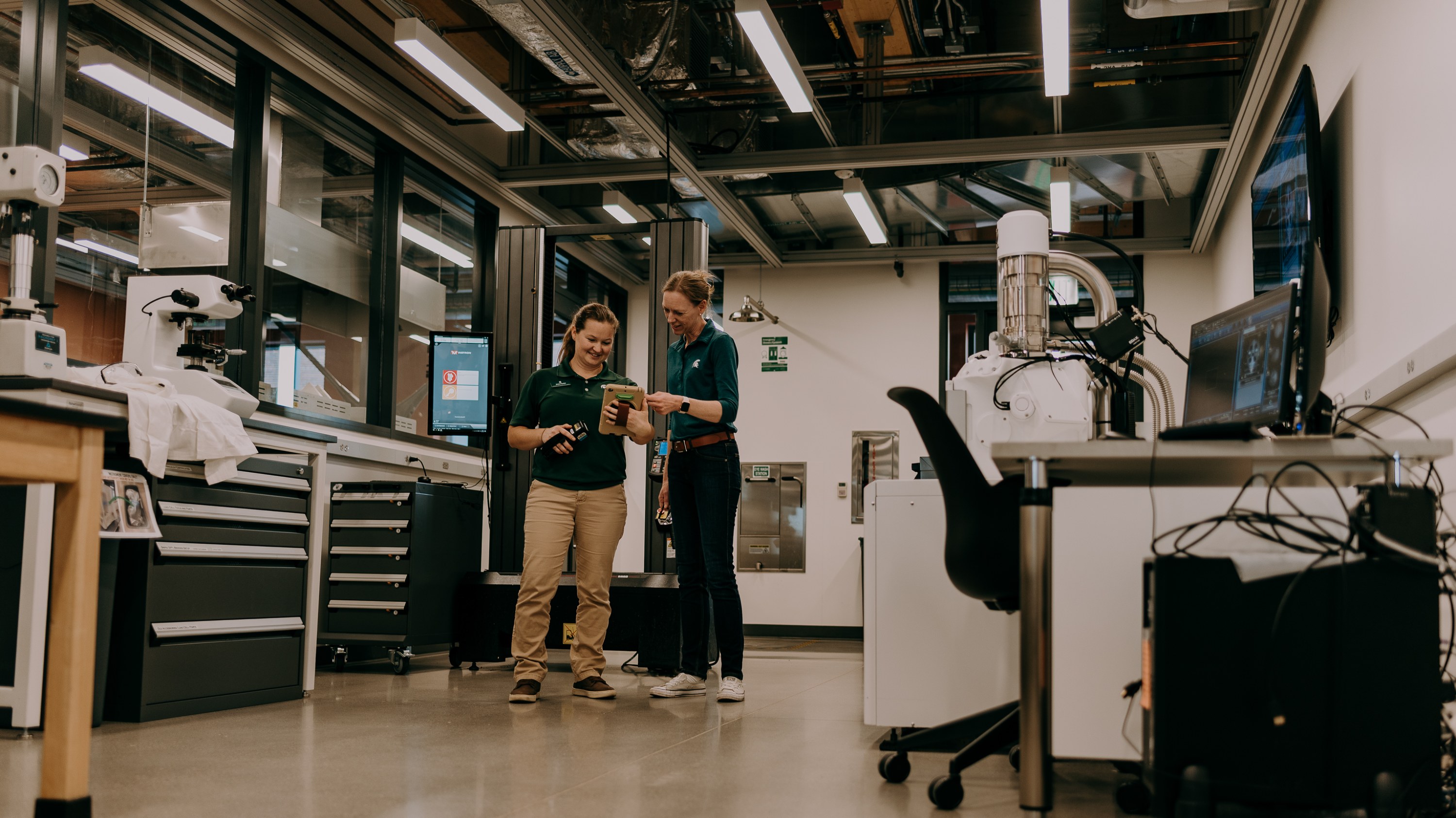 Anna Foster and Anne Eisenlohr discuss a tensile testing machine in a material sciences lab inside the STEM Teaching and Learning Facility.