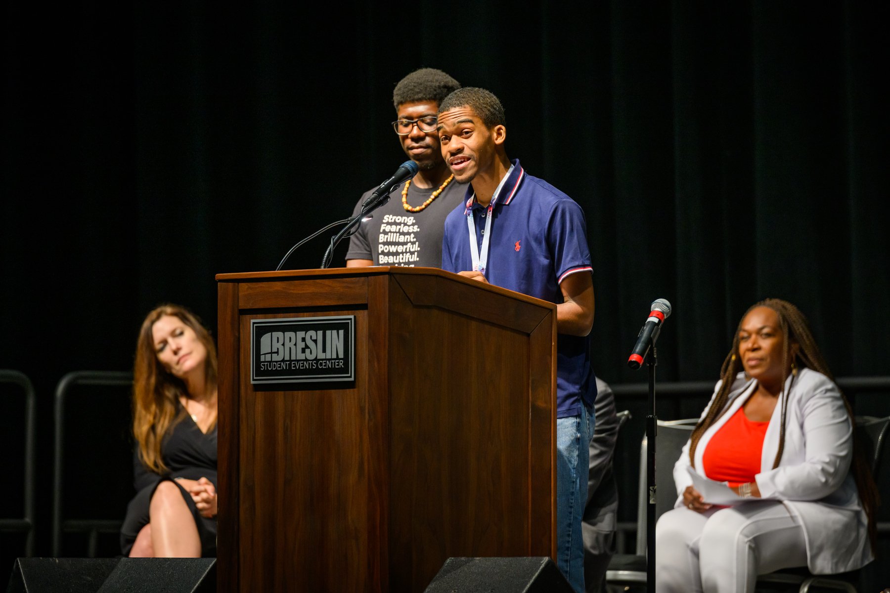 Marcus McDaniel speaks at the lectern with Antonio White flanking him on his left hand side and flanked in the background by Renee Knake Jefferson on the left and Stephanie Anthony on the right.