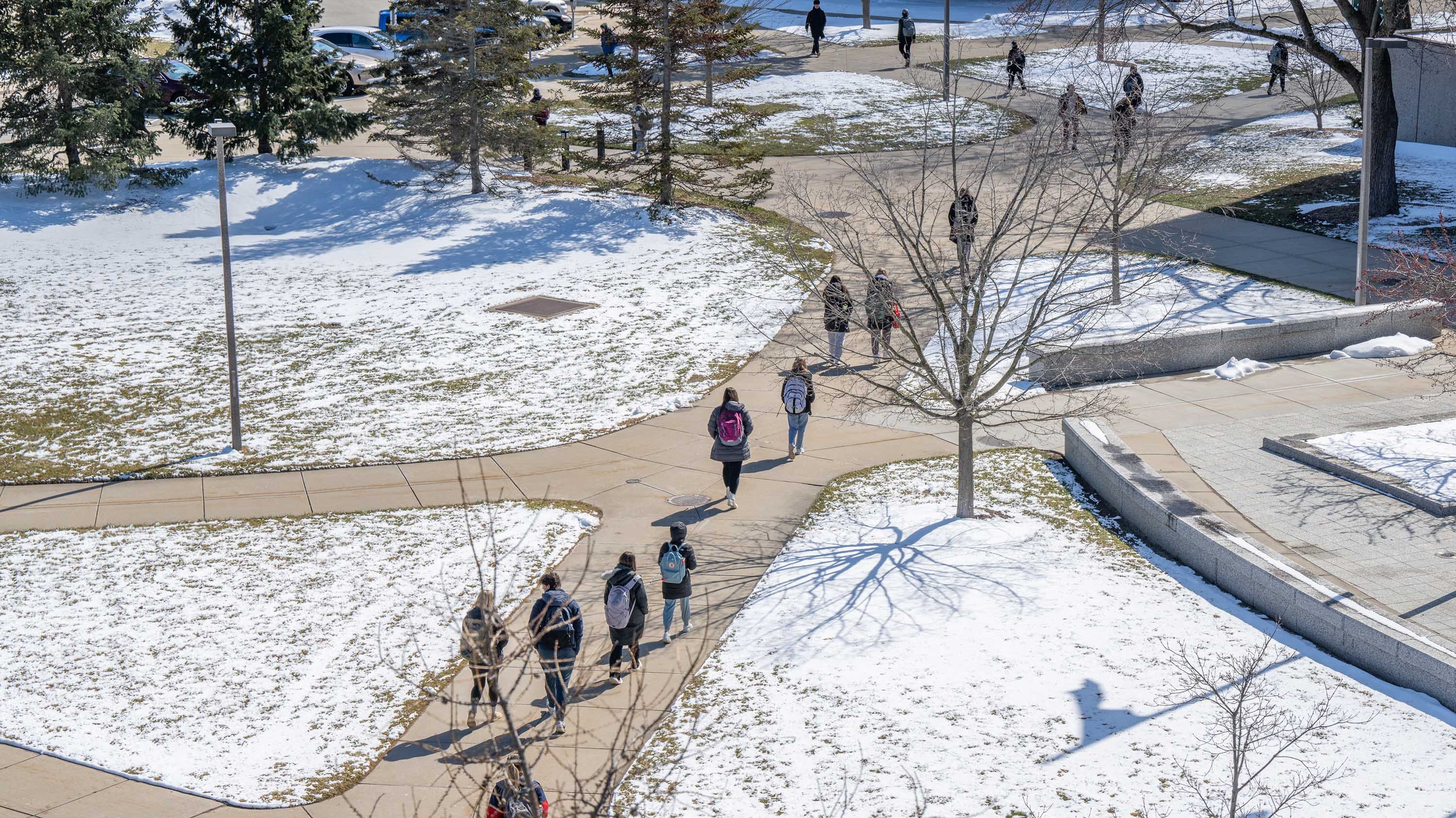 Students walking on sidewalk on campus, in winter