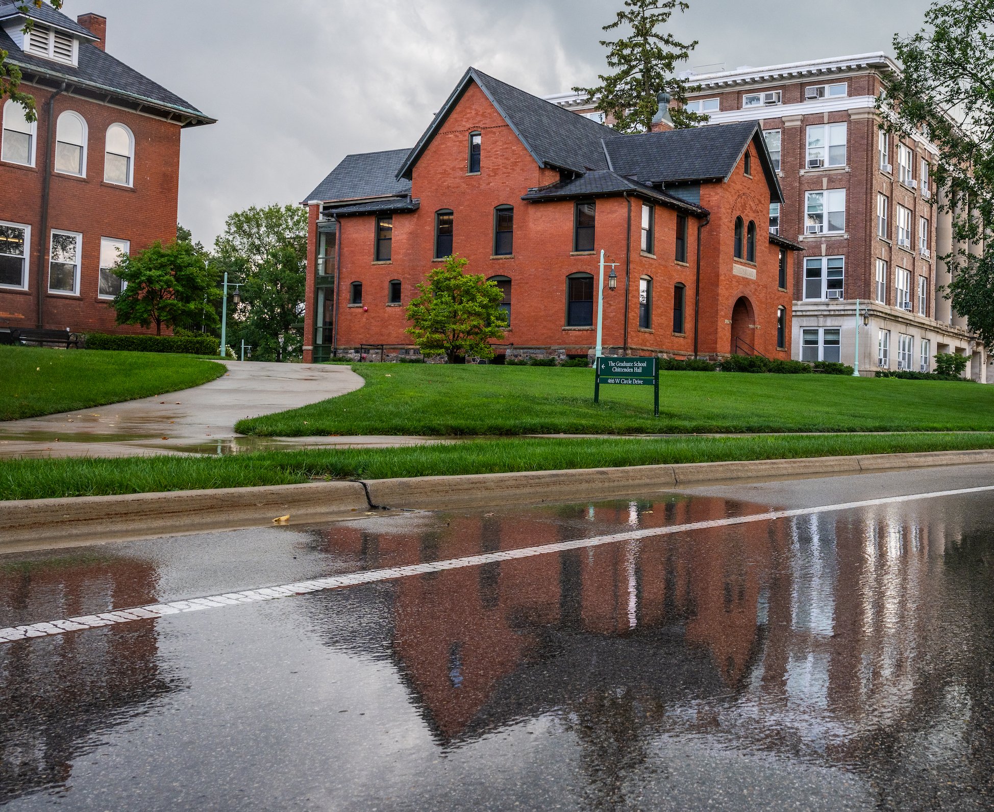 Water gathers on West Circle Drive after a rain shower, displaying the reflections of Chittenden Hall, Cook-Seevers Hall and Morrill Hall of Agriculture. 