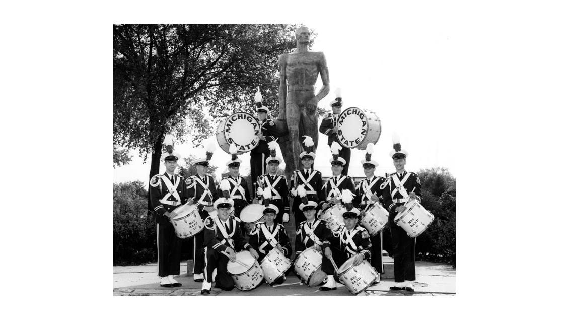 Members of the MSU Marching Band's percussion section pose by the Spartan statue. From 1962.