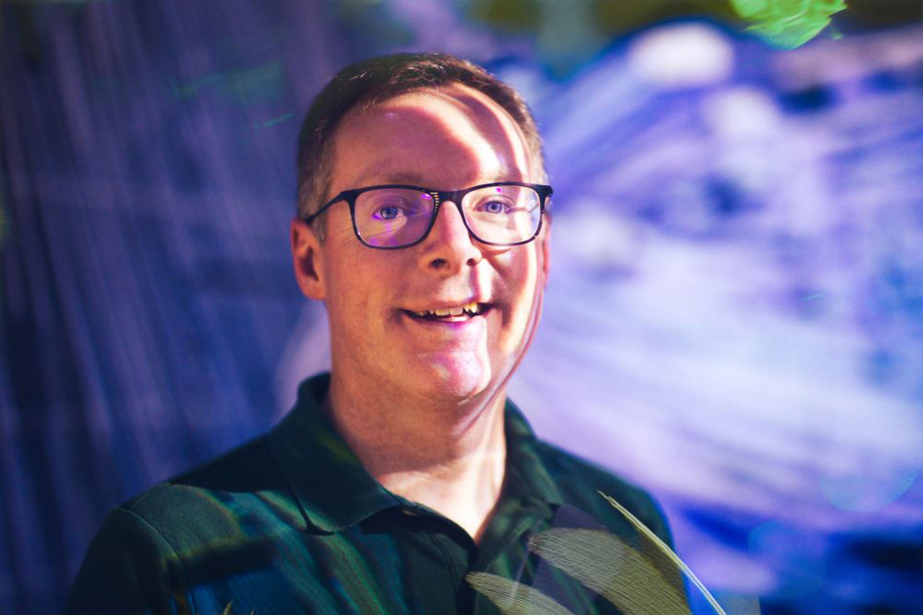MSU Associate Dean and Professor Bill Hart-Davidson in front of a background of projected and shifting blue light.