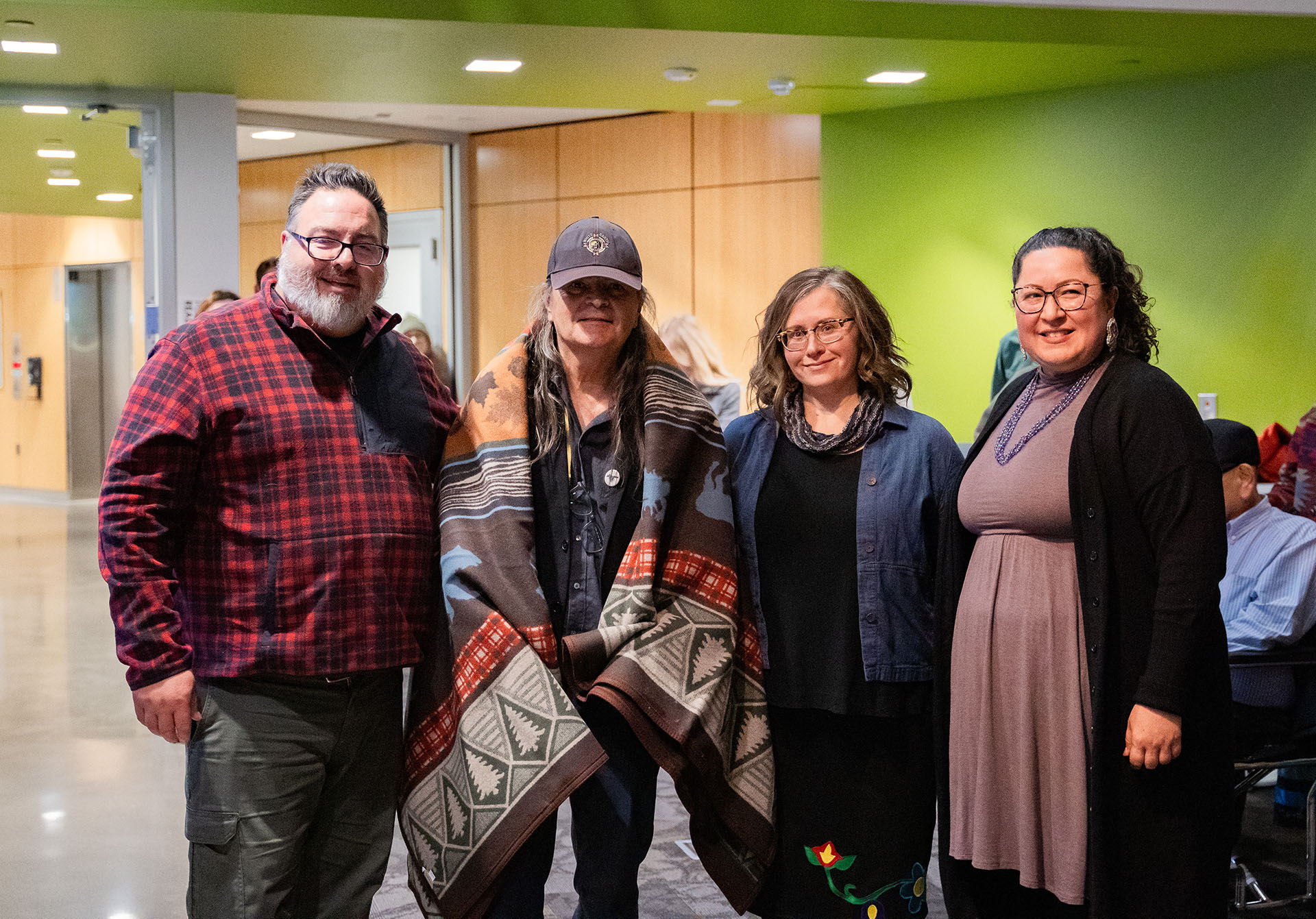 Kevin Leonard, Kristin Arola abd Emily Sorroche stand with Gordon Henry Jr. with blanket over his shoulders