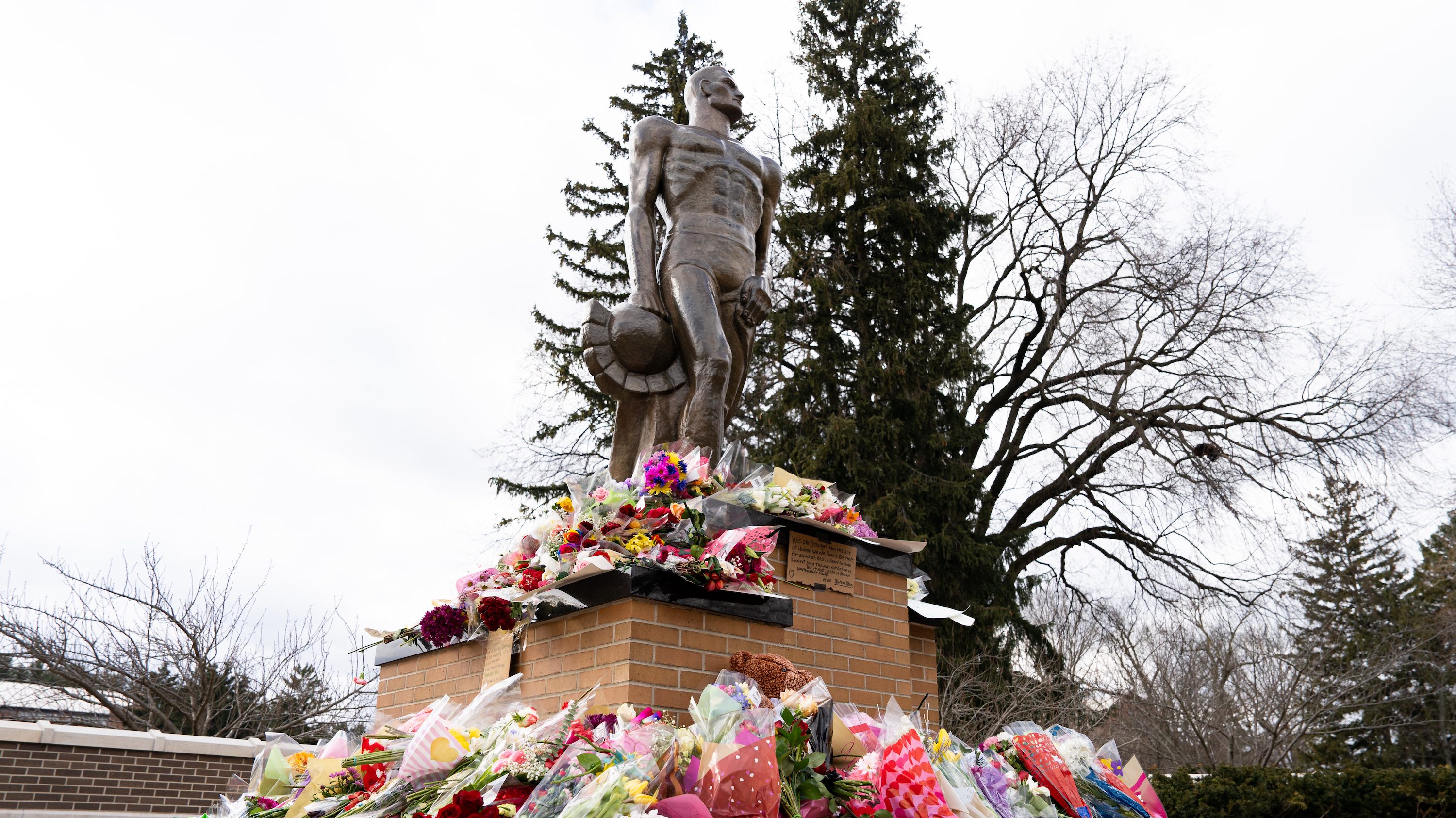 Flowers and memorial objects at the base of Spartan Statue after Feb. 13