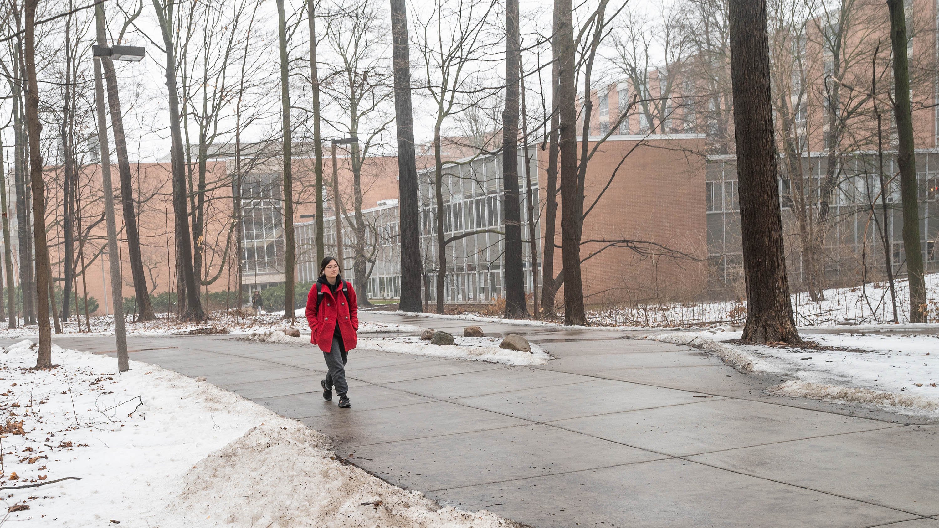 Student in red jacket walking on campus path