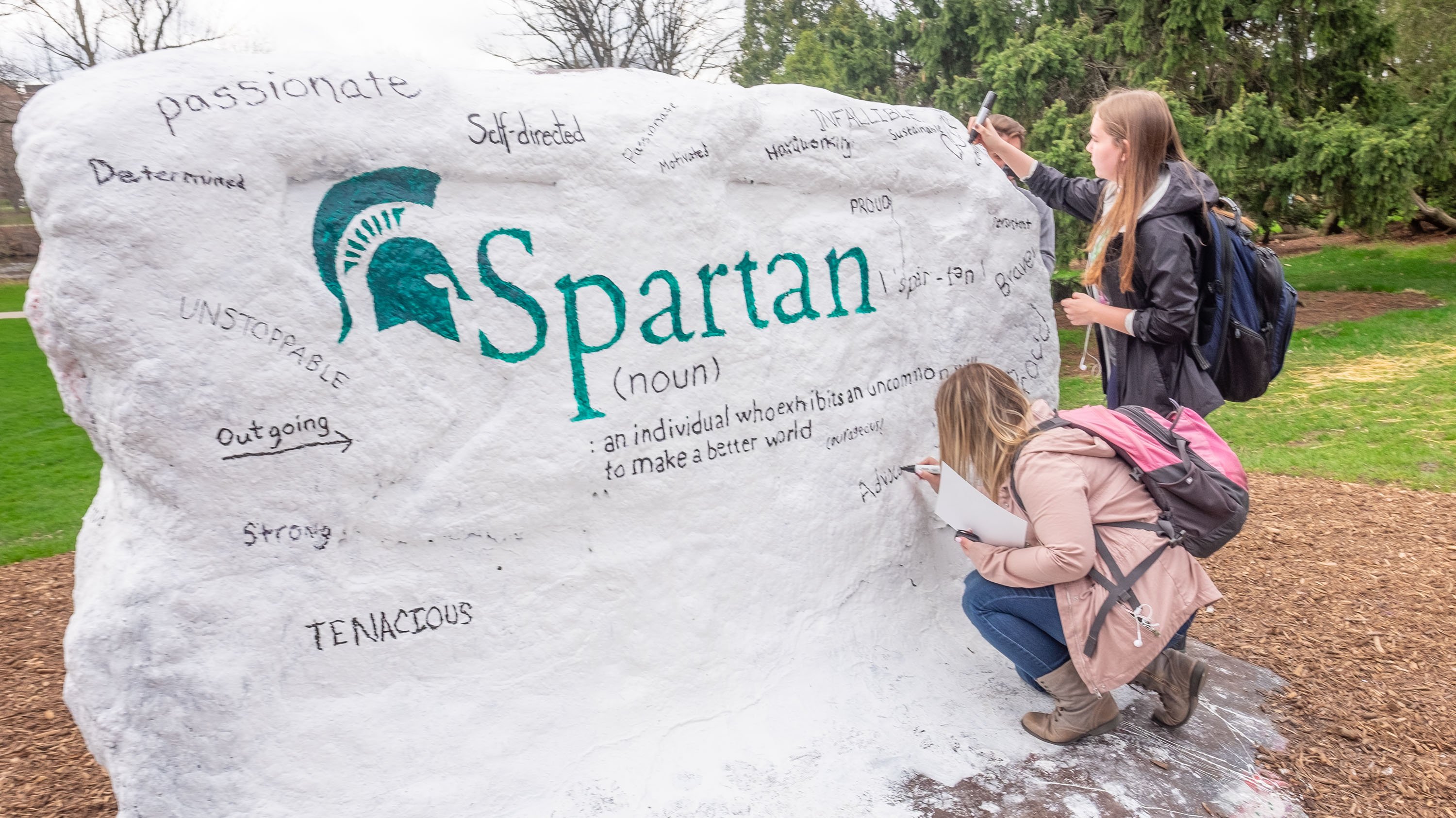 Students painting MSU Rock