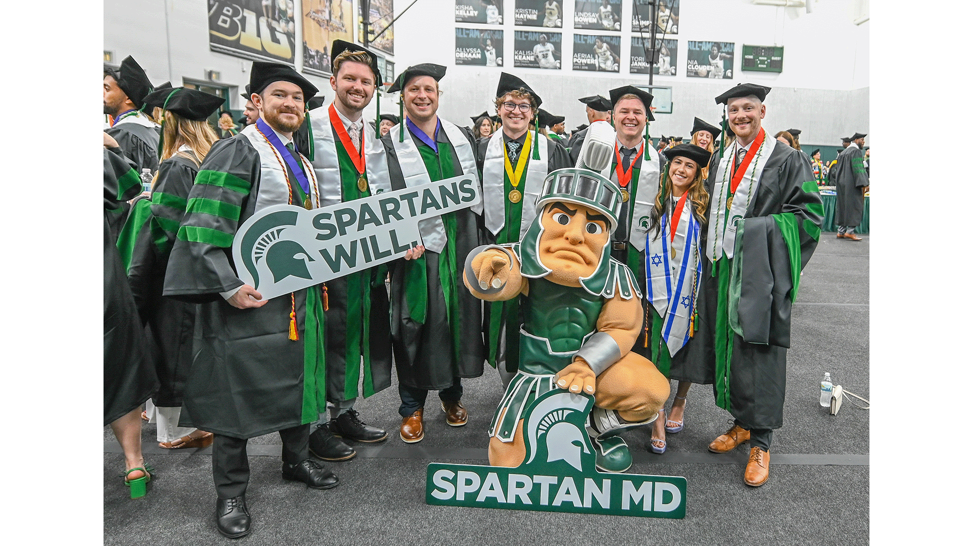 Graduates of the College of Human medicine posing with Sparty at commencement