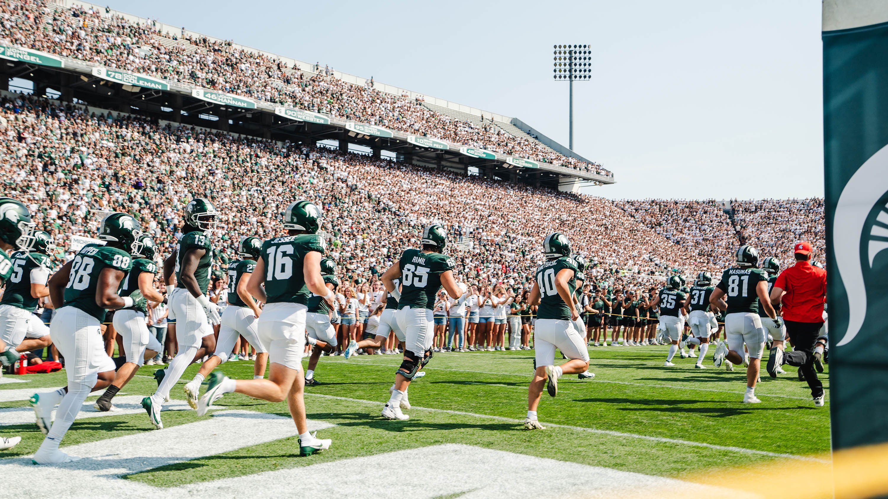 Football players running on the field at Spartan Stadium