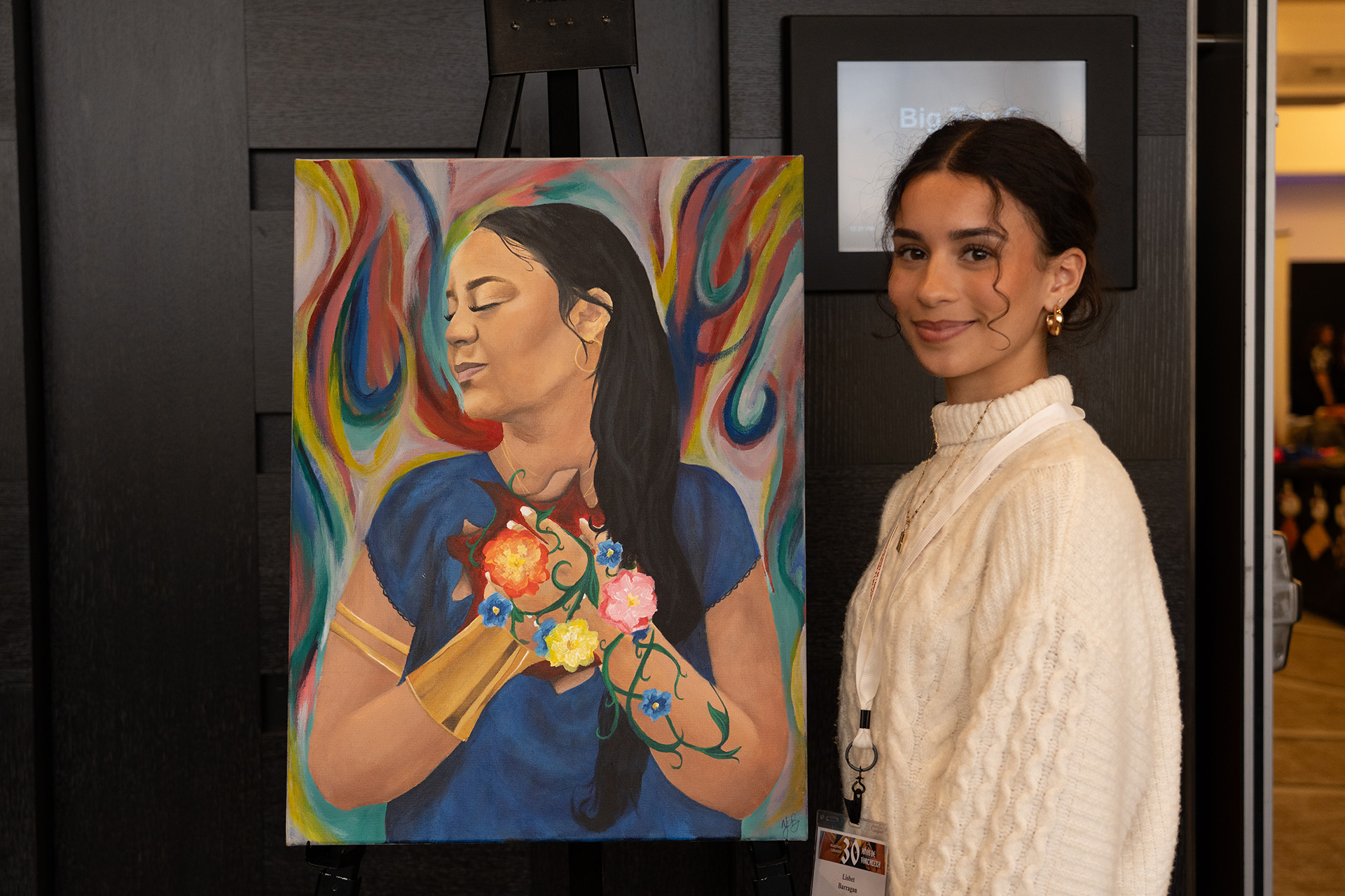 a student stands next to her painting