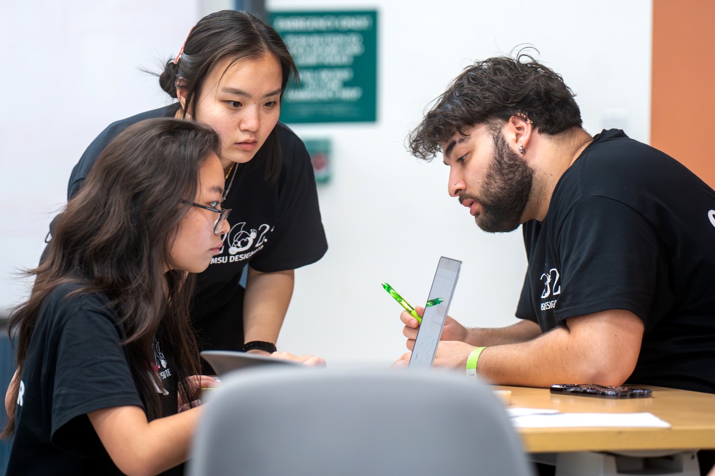 Lisa Chai, Rena Huang, and Julius Patto discussing judging for participants during the last few hours of the MSU Designathon.  (Photo by Darrian Chen)