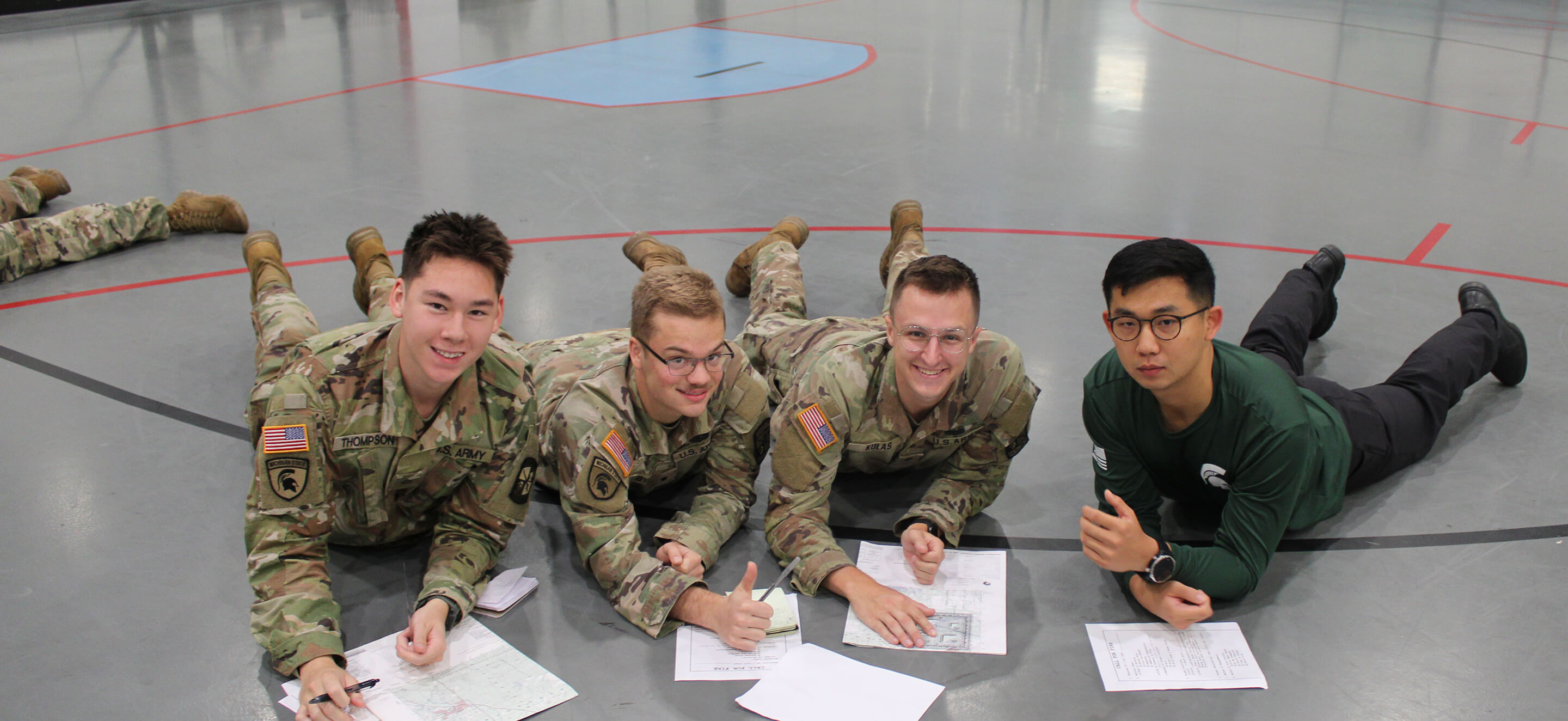 cadets work together on paperwork laying on the floor of the gym