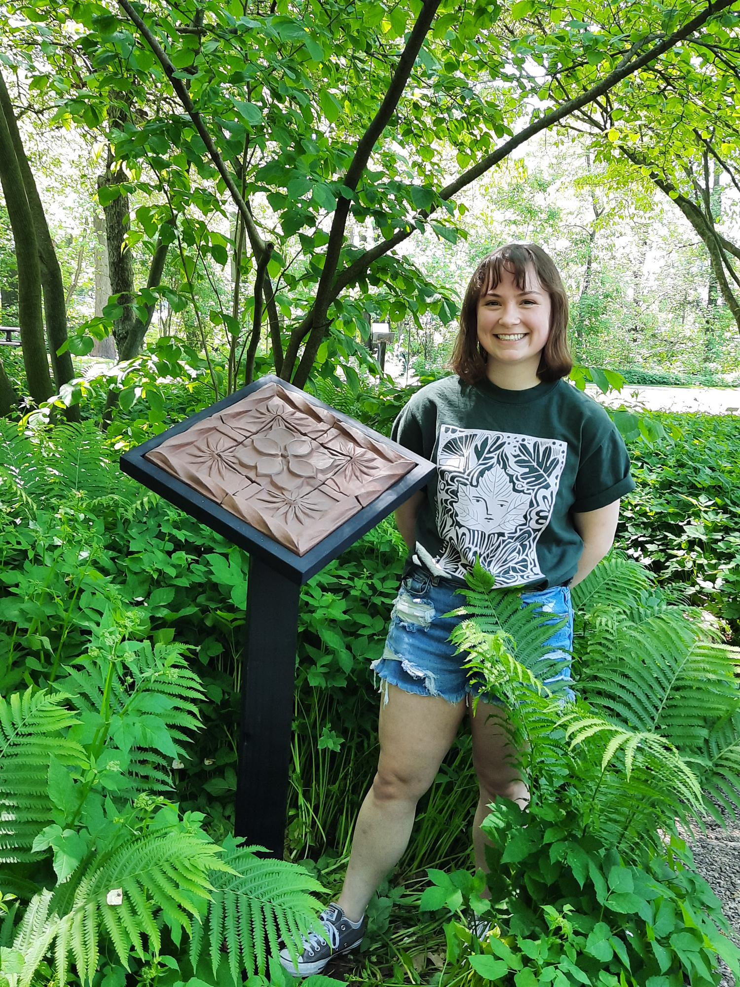 woman standing next to artwork in a garden