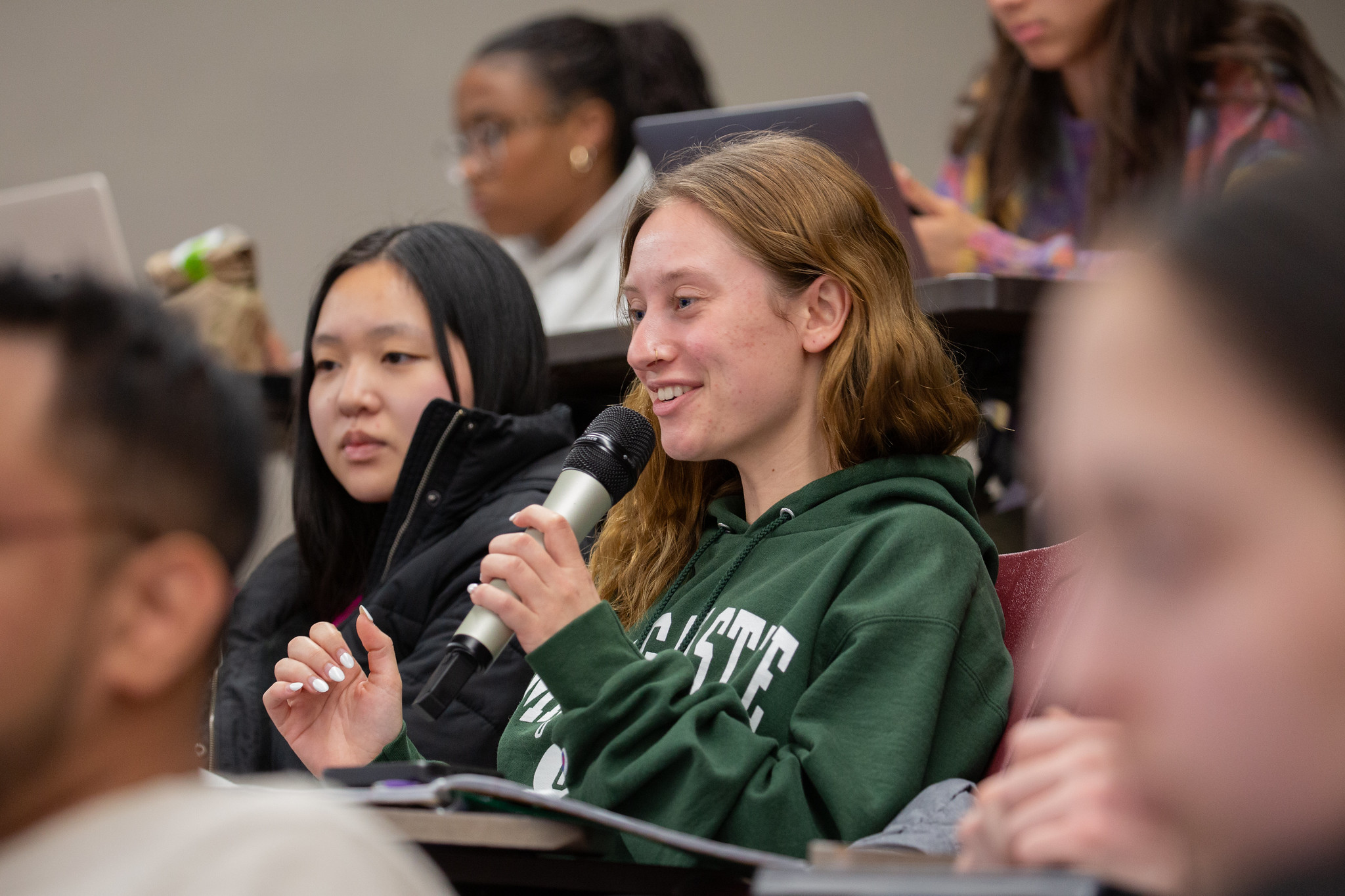 A Michigan State University student holds a microphone and asks a question during an Ethics Week 2025 lecture.