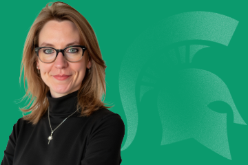 Headshot of Kate Birdsall, director for Faculty and Academic Staff Affairs, from the shoulders up with a closed-mouth smile and wearing black in front of a green background featuring a Spartan helmet logo.