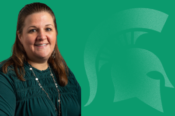 Shannon Kemp, Senior Human Resources Professional, smiling and wearing a green blouse in front of a green background featuring a Spartan helmet logo.