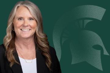 Georgette Russell, Assistant Vice President of Human Resources, smiling, wearing a black jacket over a white blouse in front of a green background featuring a Spartan helmet logo.