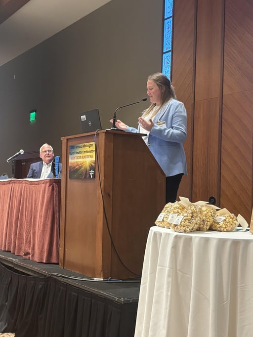 Kari Granz (at podium), Program and Communication Specialist for the Thumb Community Health Partnership, and John Barnas (sitting), Executive Director of the Michigan Center for Rural Health.