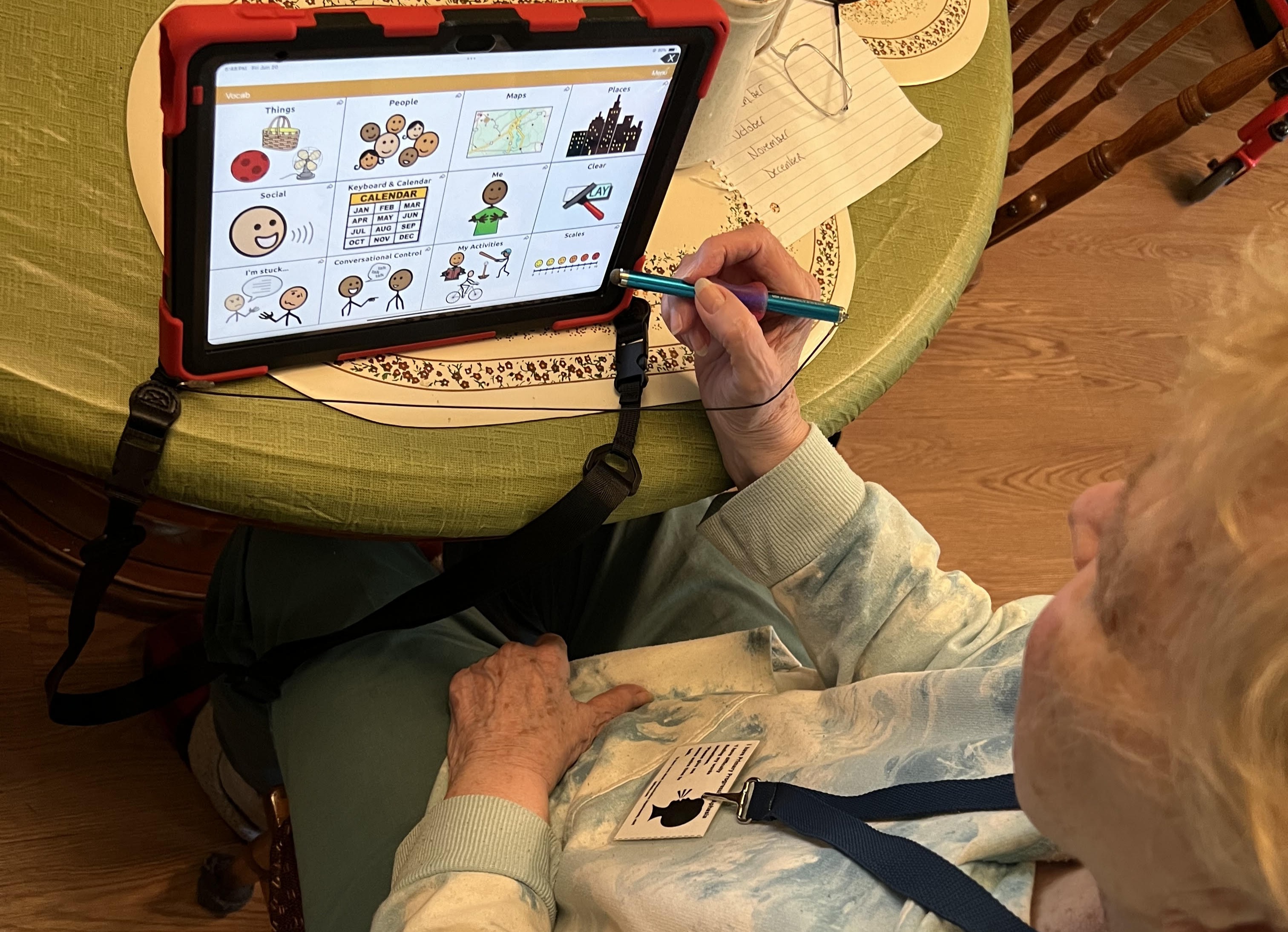 woman siting at a table with a tablet, holding a stylus. 