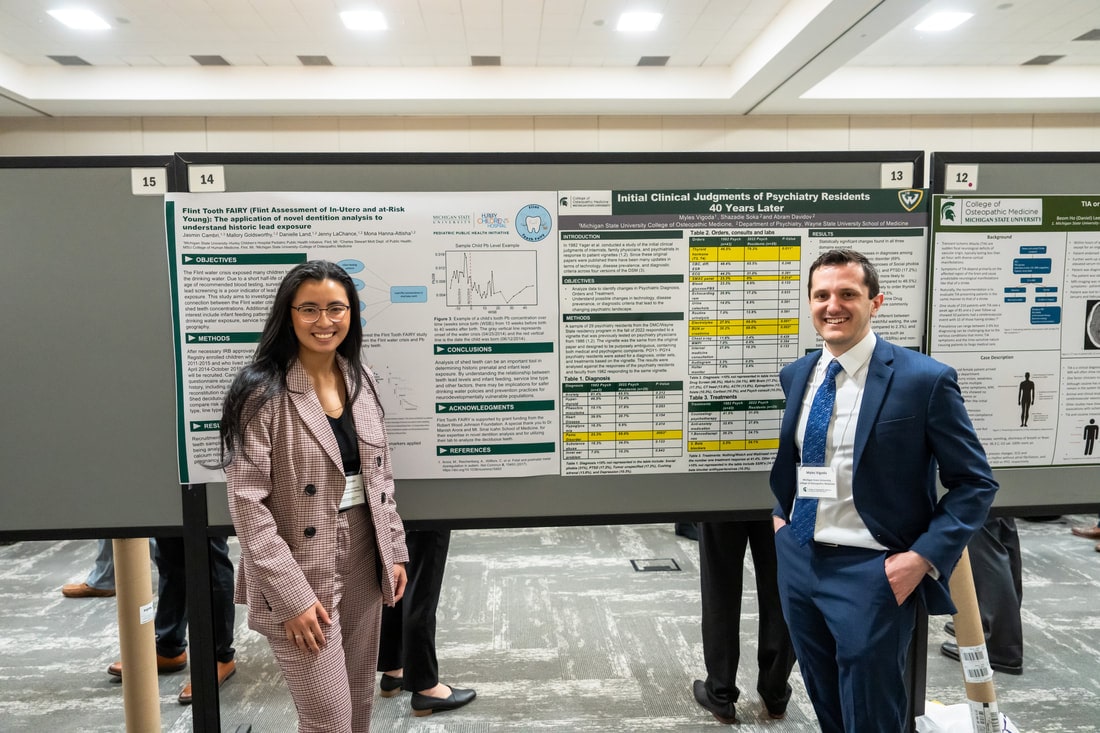 Two people standing in front of scientific posters at a conference.